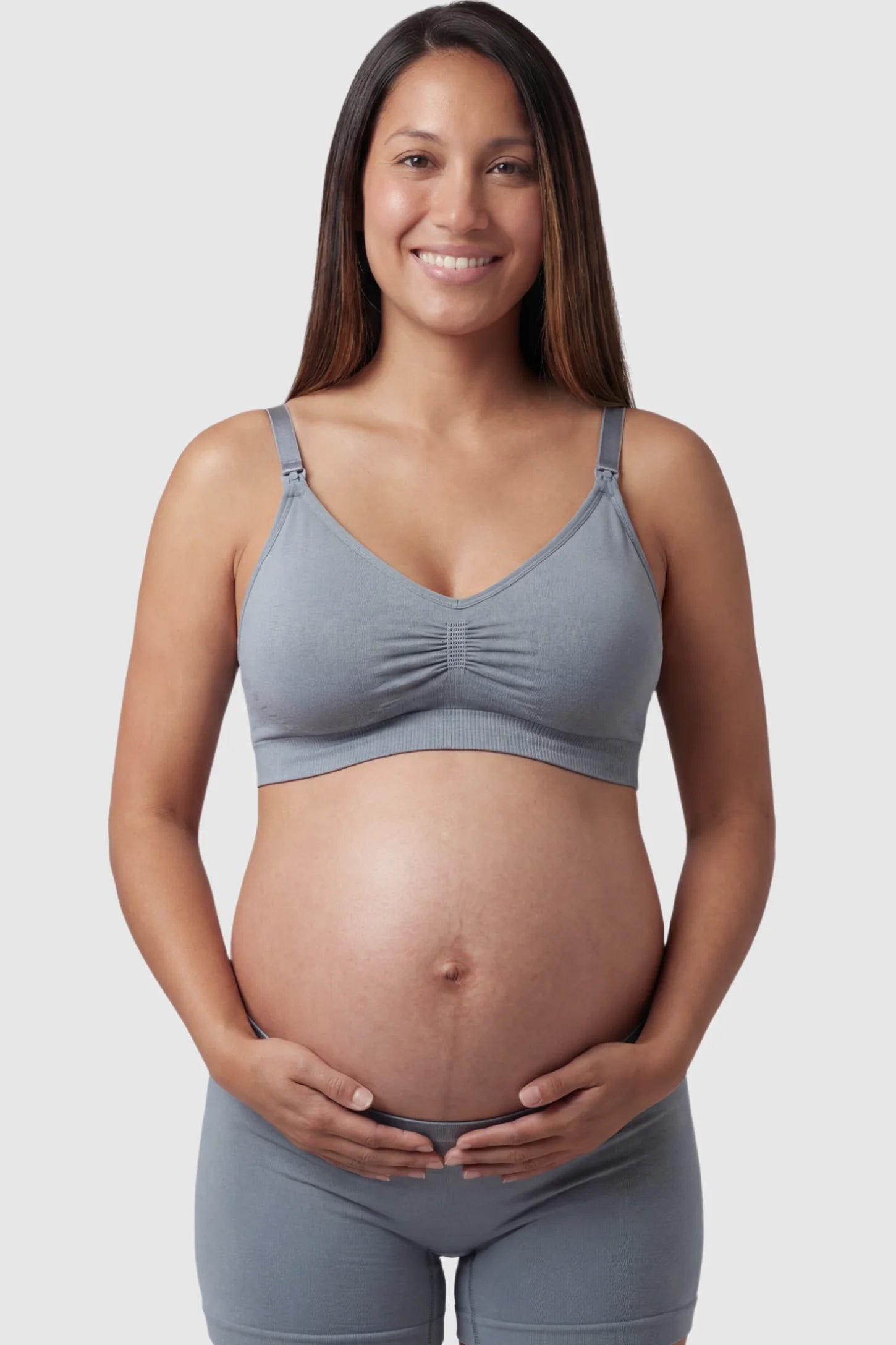 Seamless Ruched Front Maternity Nursing Bra Seamless Ruched Front Maternity Nursing Bra in gray featuring ribbed fabric and drop-down clips on a pregnant model showing front.