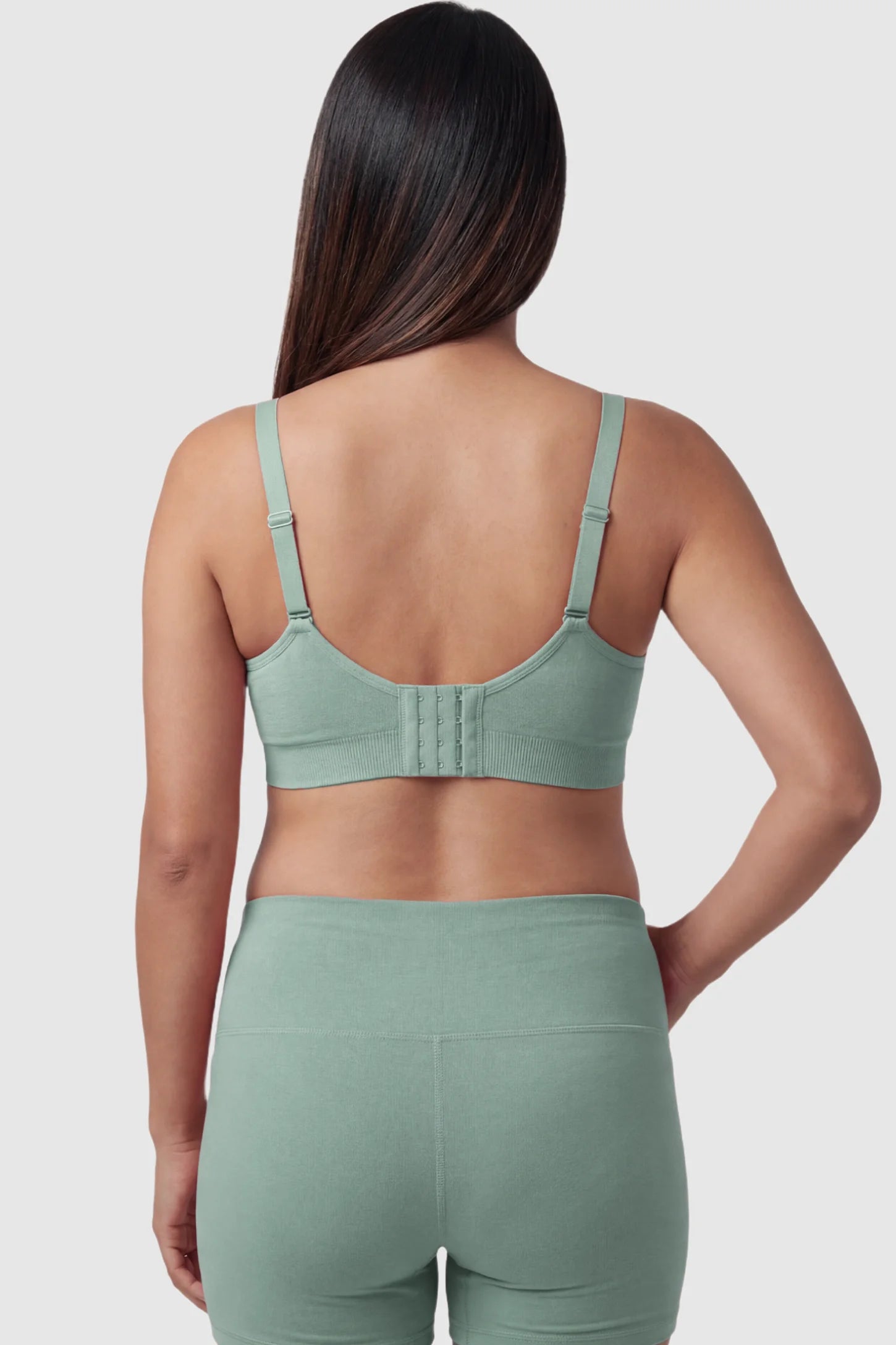 Seamless Ruched Front Maternity Nursing Bra Seamless Ruched Front Maternity Nursing Bra in green featuring ribbed fabric, adjustable straps, and a multi-hook back closure on a pregnant model from behind.