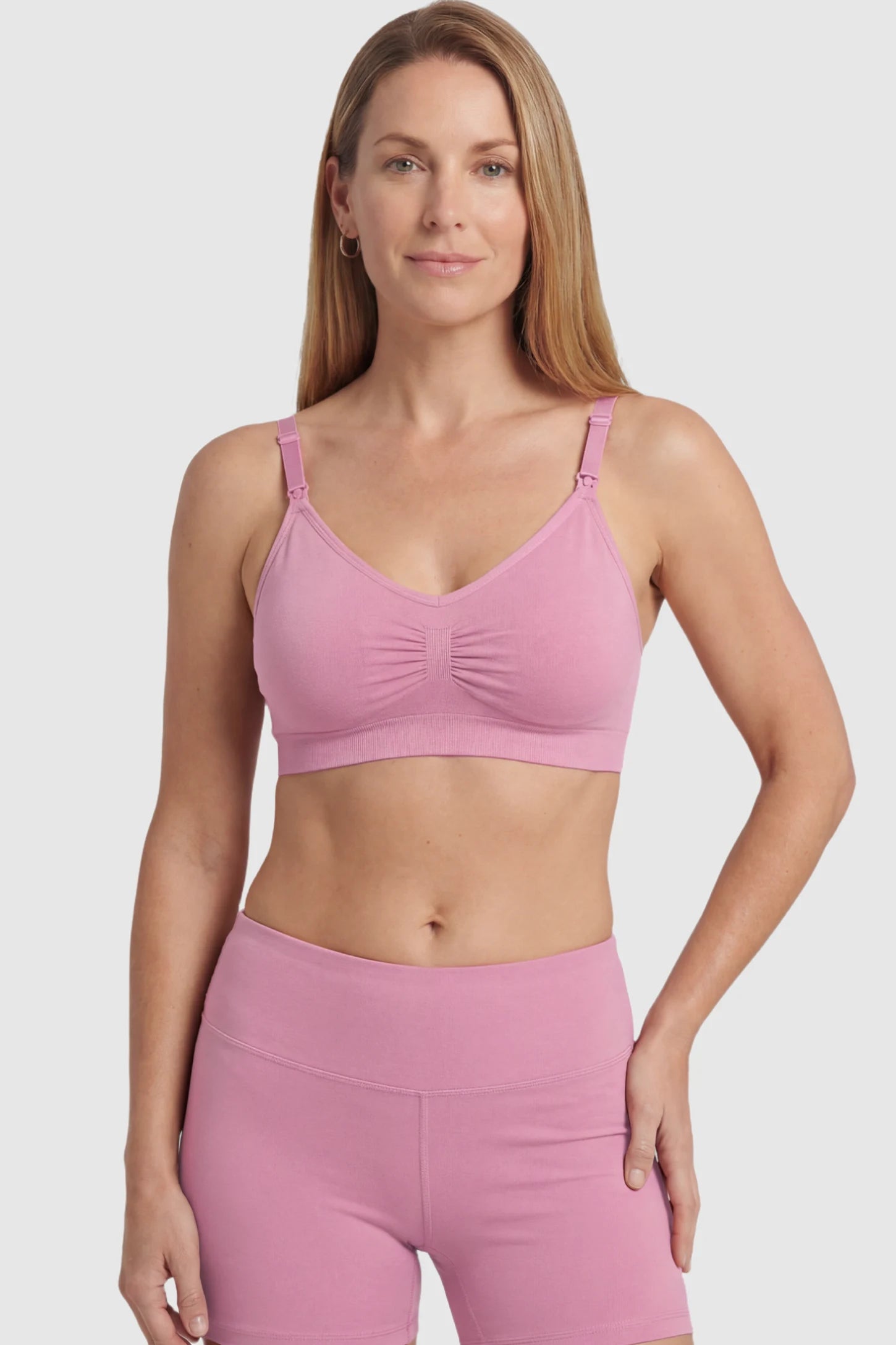 Seamless Ruched Front Maternity Nursing Bra Seamless Ruched Front Maternity Nursing Bra in peach pink featuring ribbed fabric and drop-down clips on a postpartum model showing front.