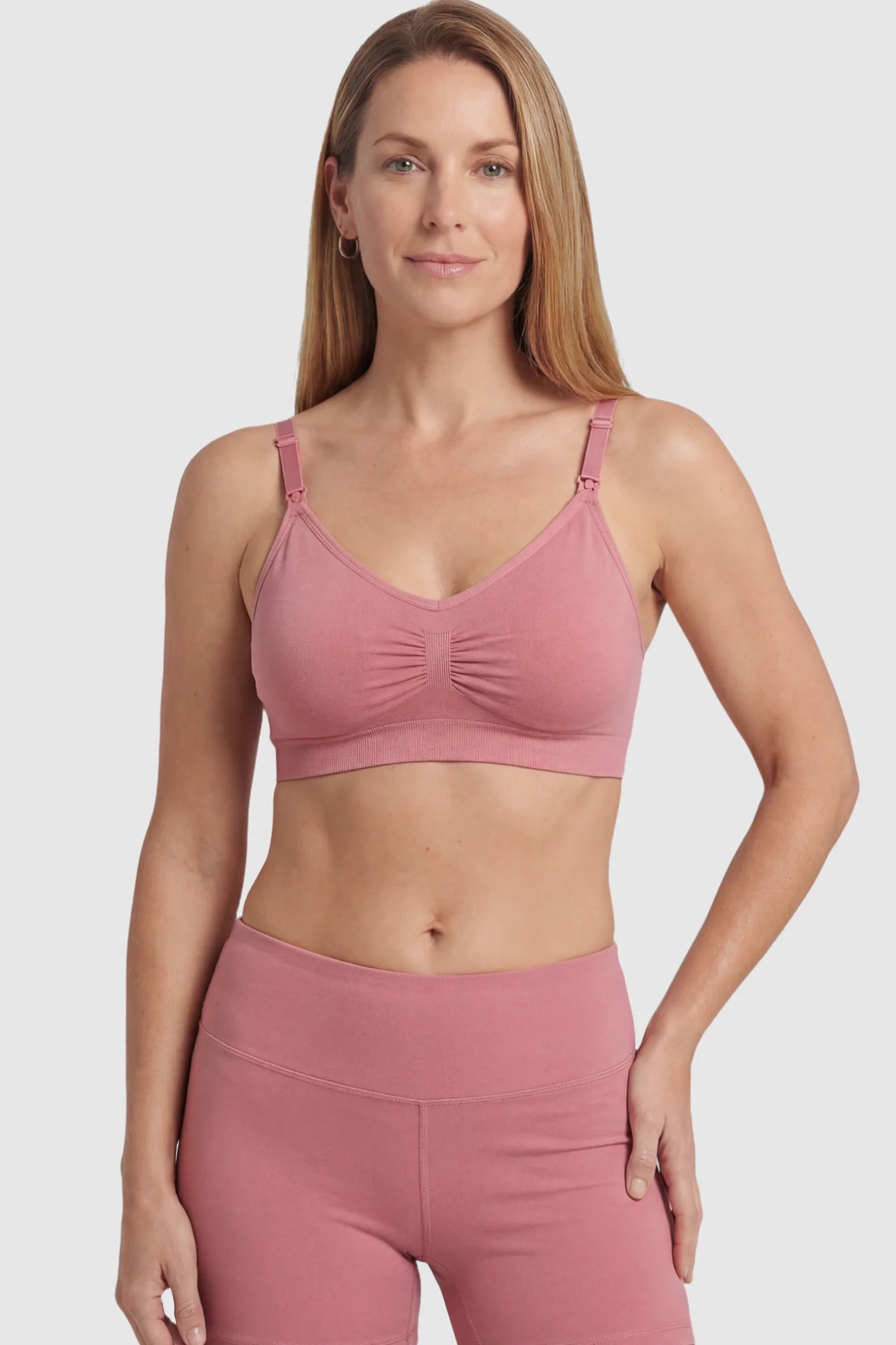 Seamless Ruched Front Maternity Nursing Bra Seamless Ruched Front Maternity Nursing Bra in pink featuring ribbed fabric and drop-down clips on a postpartum model showing front.