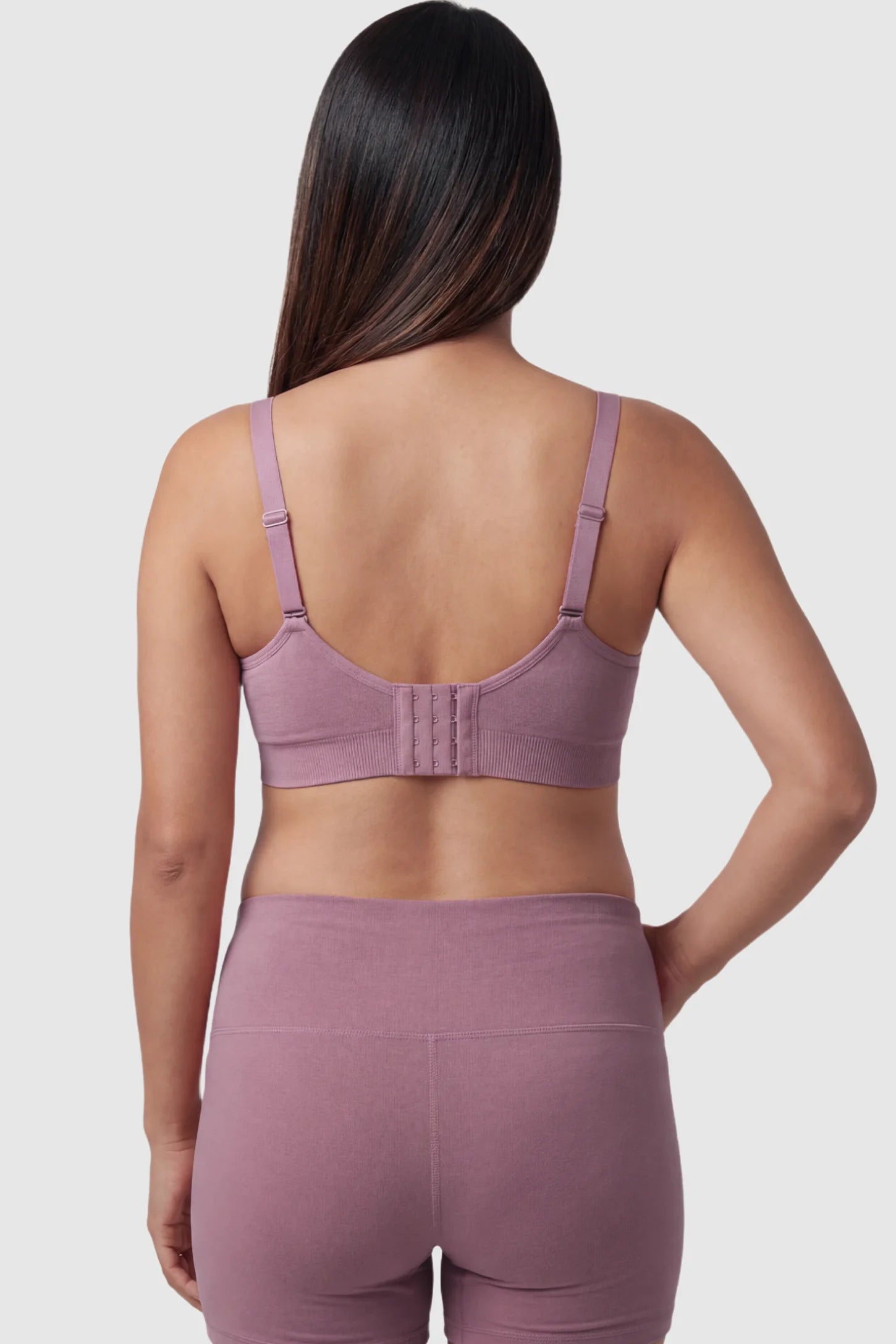 Seamless Ruched Front Maternity Nursing Bra Seamless Ruched Front Maternity Nursing Bra in purple featuring ribbed fabric, adjustable straps, and a multi-hook back closure on a pregnant model from behind.
