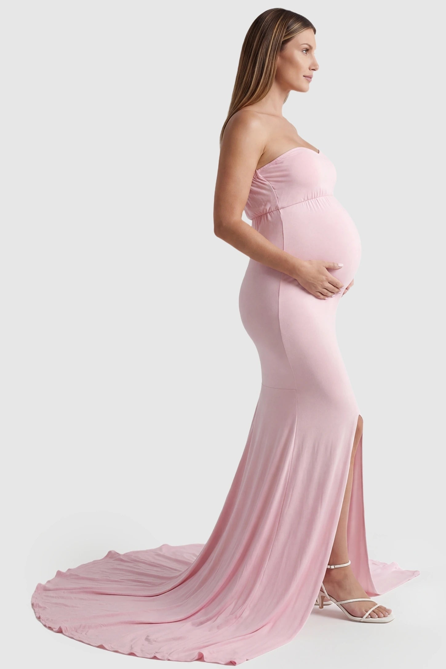 Strapless Sweetheart Neckline Trumpet Silhouette Maternity Gown Strapless Sweetheart Neckline Trumpet Silhouette Maternity Gown in Pink featuring a long train on a pregnant model, side view.