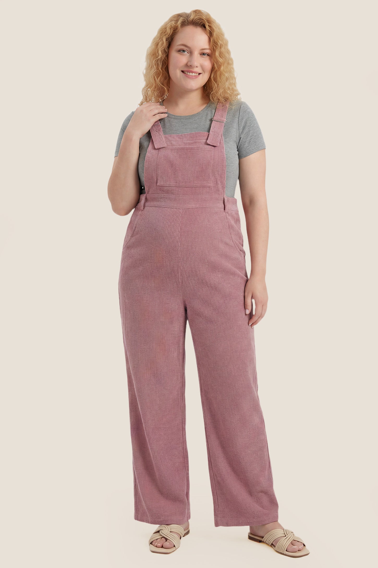 Side view of pink corduroy wide leg maternity jumpsuit with bump-friendly fit