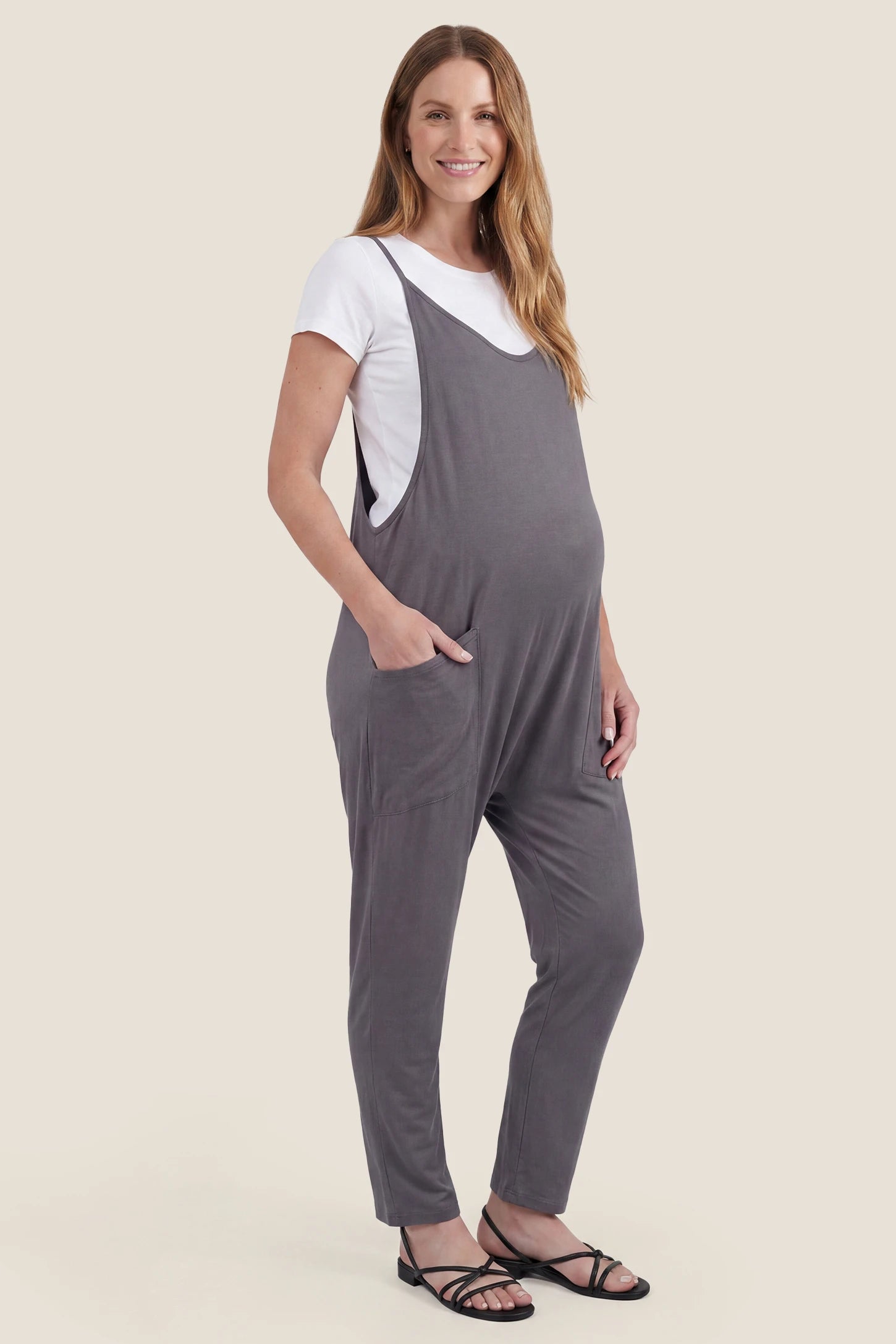 Adjustable Strap Pocketed Relaxed Maternity Jumpsuit Side view of dark gray adjustable strap pocketed relaxed maternity jumpsuit with bump-friendly fit
