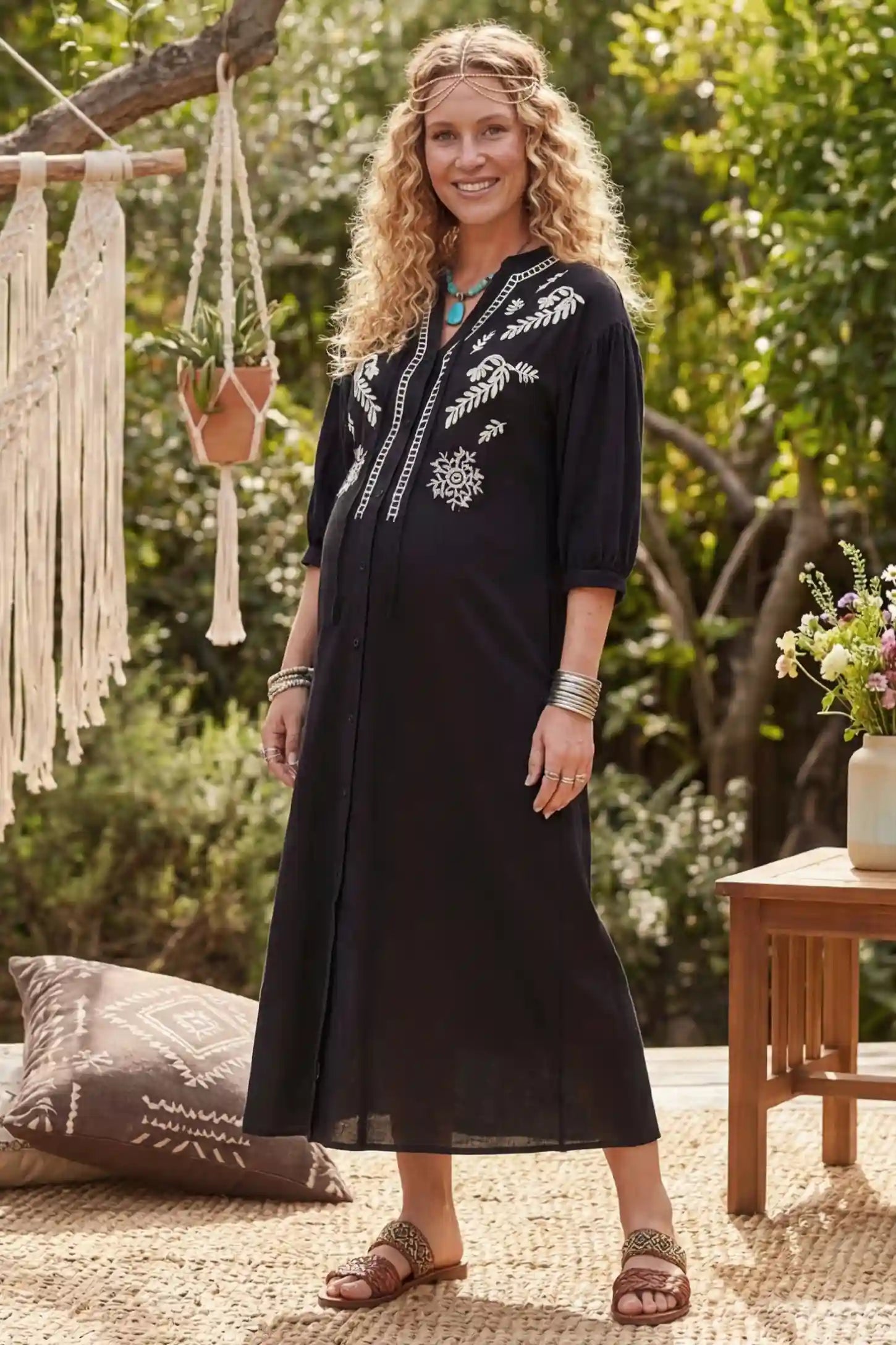 Embroidered Notched Half Sleeve Maternity Midi Dress Side view of Black Embroidered Notched Half Sleeve Maternity Midi Dress featuring white floral embroidery on a pregnant model.