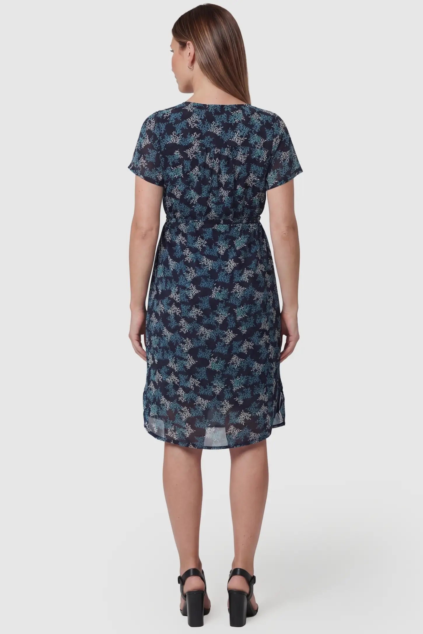 Floral V-Neck Knee-Length Maternity & Nursing Dress Floral V-Neck Knee-Length Maternity & Nursing Dress in Blue featuring short sleeves and a knee-length hem on a pregnant model, back view.