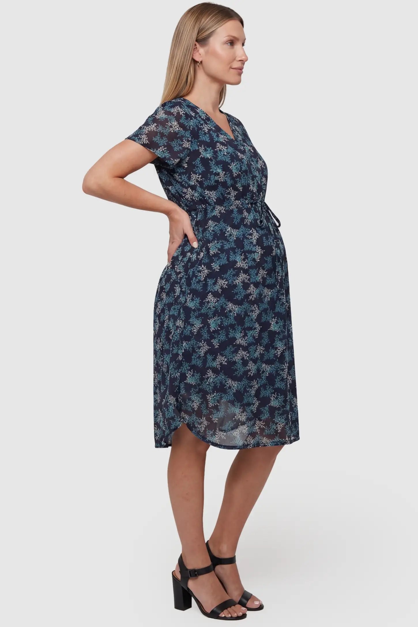 Floral V-Neck Knee-Length Maternity & Nursing Dress in Blue featuring a high-elastic fitted waist on a pregnant model, side view.