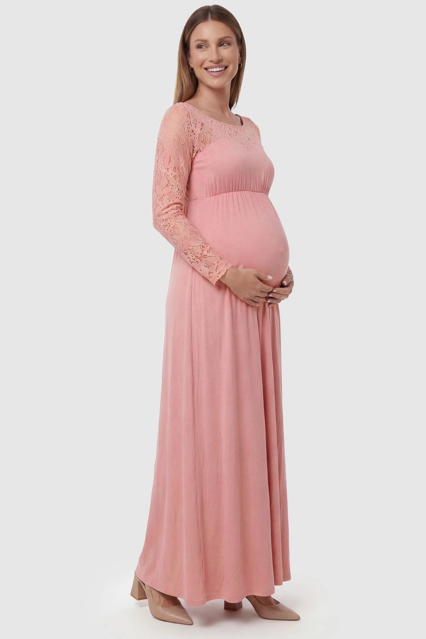Acrylic Lace Long Sleeve Floor-Length Maternity Dress Acrylic Lace Long Sleeve Floor-Length Maternity Dress in Pink featuring lace-spliced sleeves on a side-profile pregnant model.