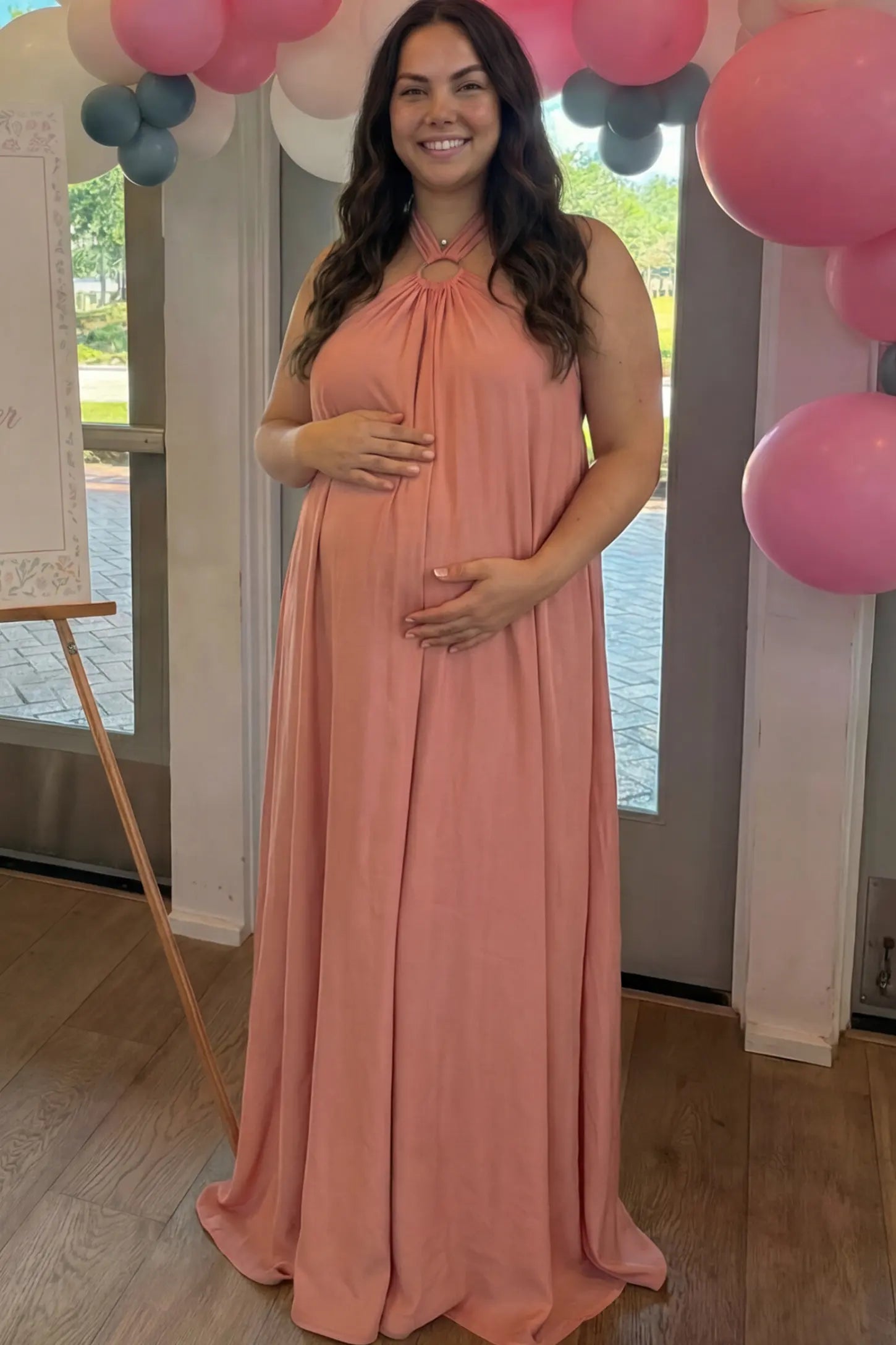 Solid Halter Neck Maternity Maxi Dress Solid Halter Neck Maternity Maxi Dress in Pink featuring a flowing skirt on a pregnant model.