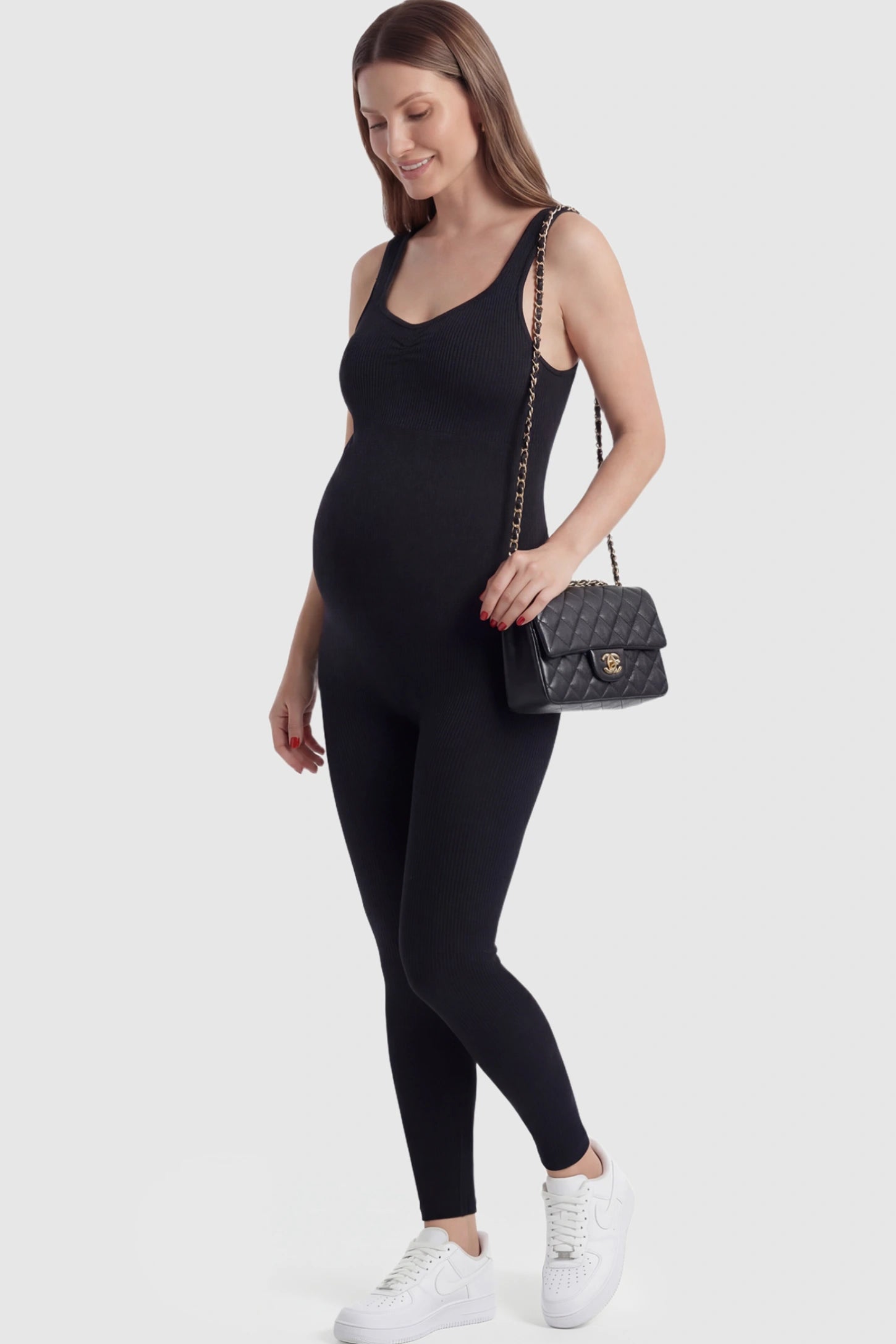 Scoop Neck Sleeveless Ribbed Bodycon Maternity Jumpsuit in Black featuring a seamless texture on a pregnant model.