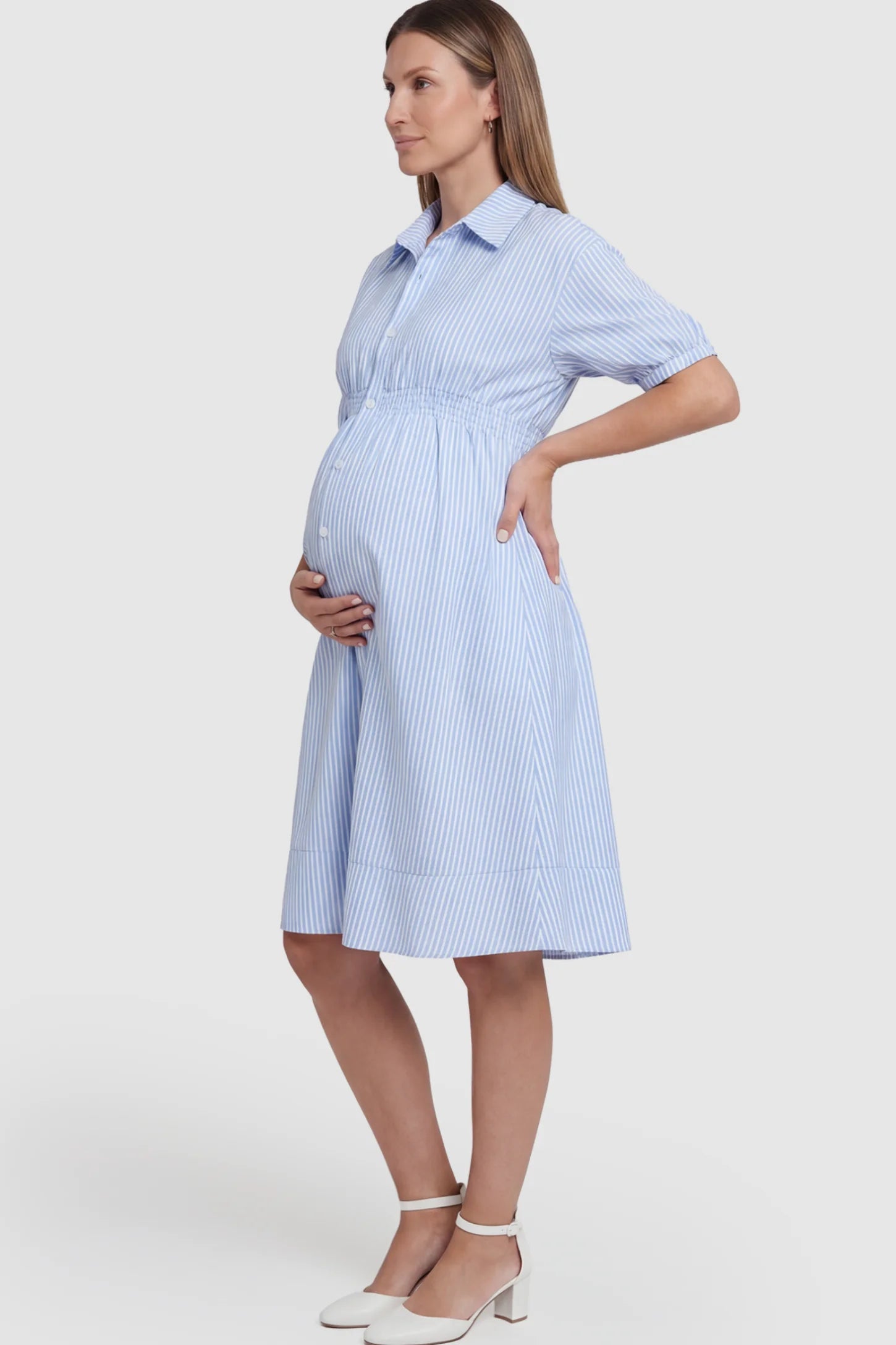 Striped Smocked-Waist Button-Down Maternity Shirt Dress in light blue and white stripes featuring a collared neckline and short sleeves on a pregnant model.