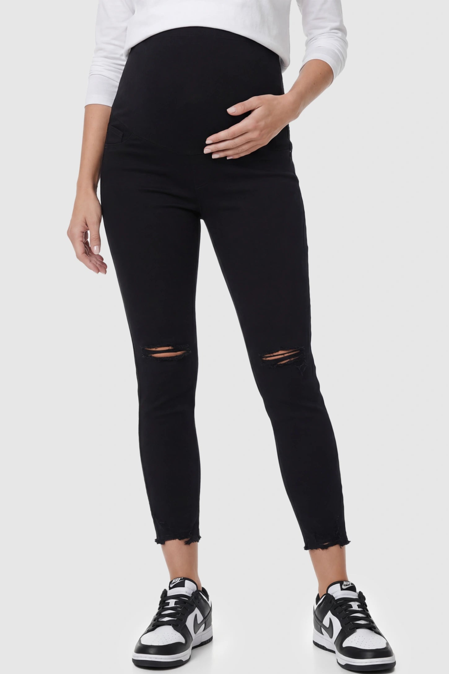 Stretch Panel Distressed Skinny Maternity Jeans in Black featuring a high-rise elastic waistband and ripped knees on a pregnant model.