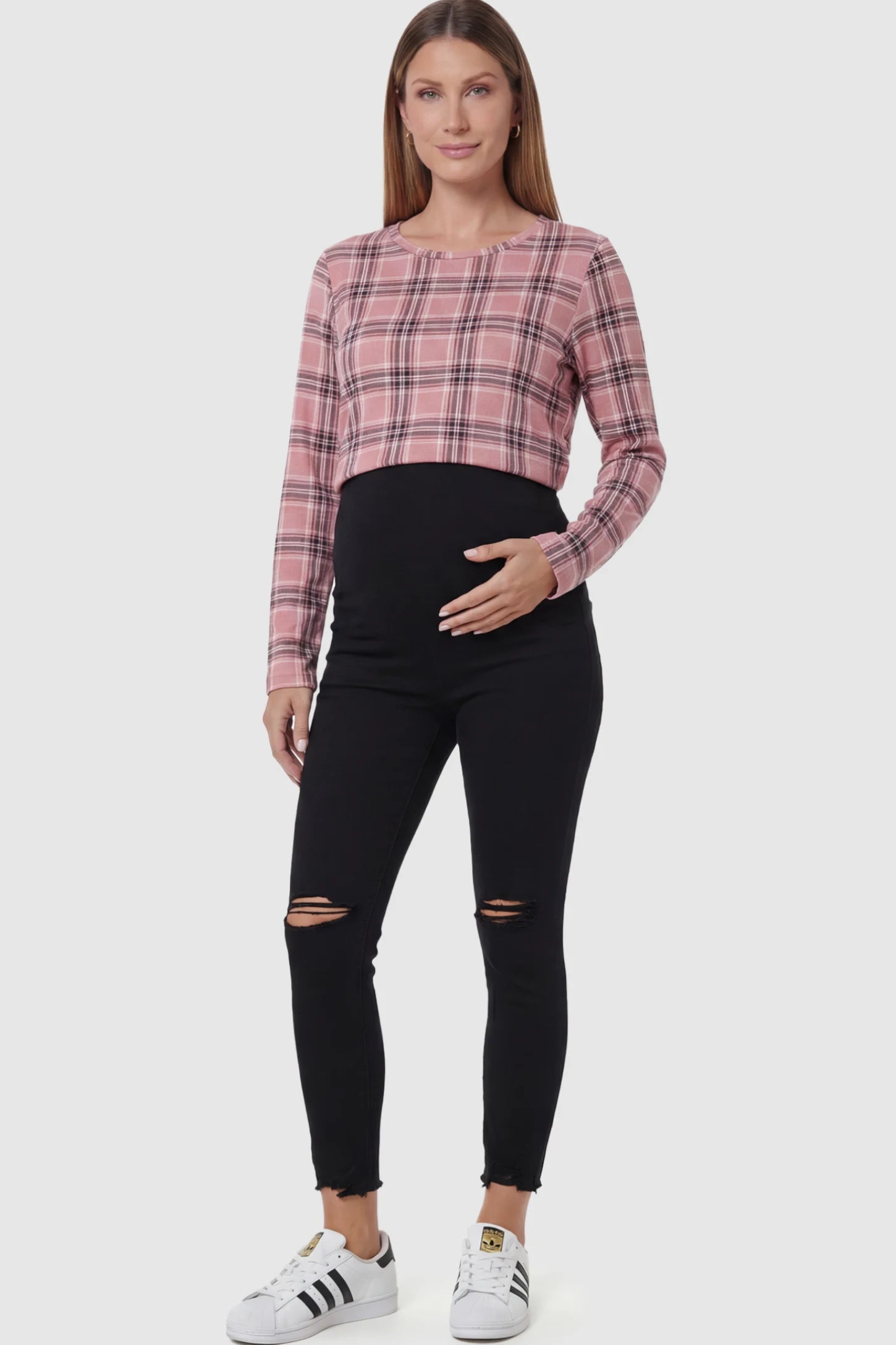 Stretch Panel Distressed Skinny Maternity Jeans Stretch Panel Distressed Skinny Maternity Jeans in Black featuring a high-rise elastic waistband and ripped knees on a pregnant model.
