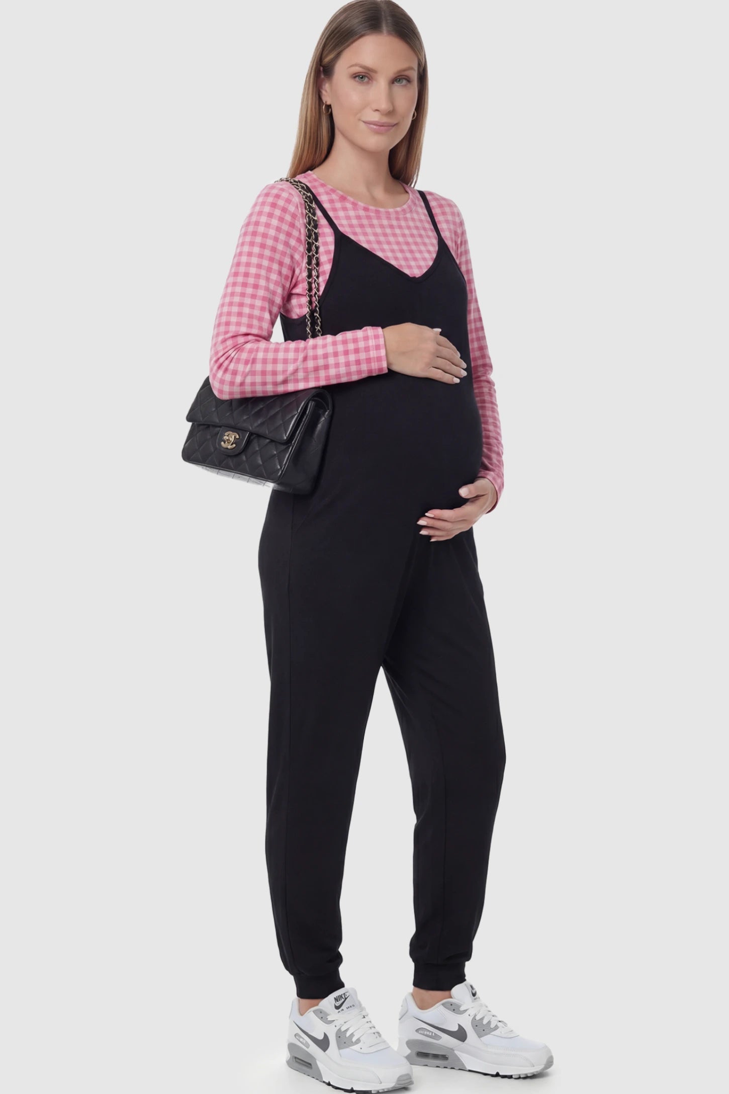V-Neck Pocketed Maternity Jogger Jumpsuit in Black featuring cotton-spandex jersey and side pockets on a pregnant model.