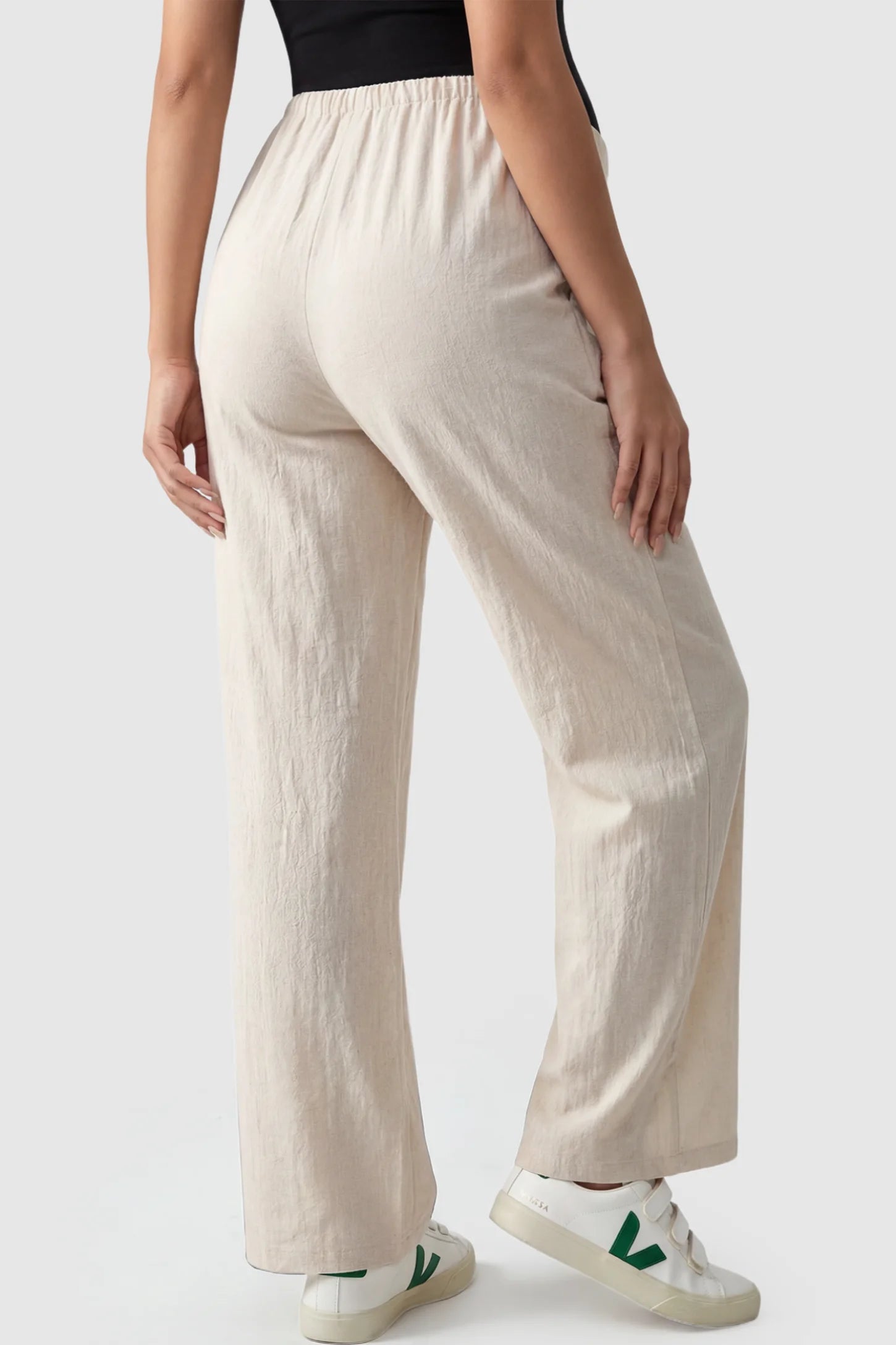 Adjustable Elastic Waist Wide Leg Maternity Pants Adjustable Elastic Waist Wide-Leg Maternity Pants in Beige featuring a customizable button-hole waistband on a pregnant model showing back.