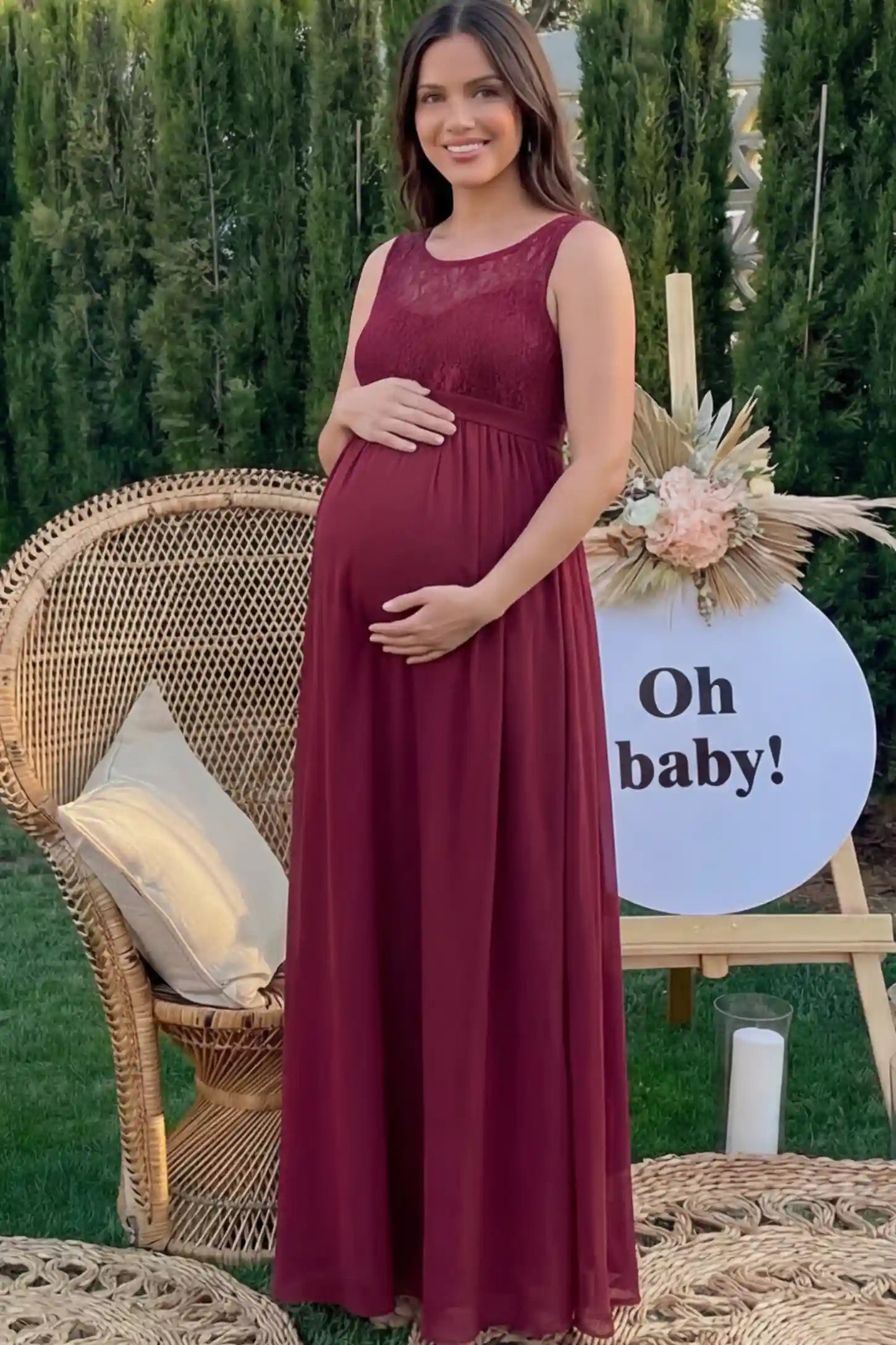 Floral Lace Sleeveless Maternity Maxi Dress Floral Lace Sleeveless Maternity Maxi Dress in Burgundy featuring a flowing skirt on a pregnant model.
