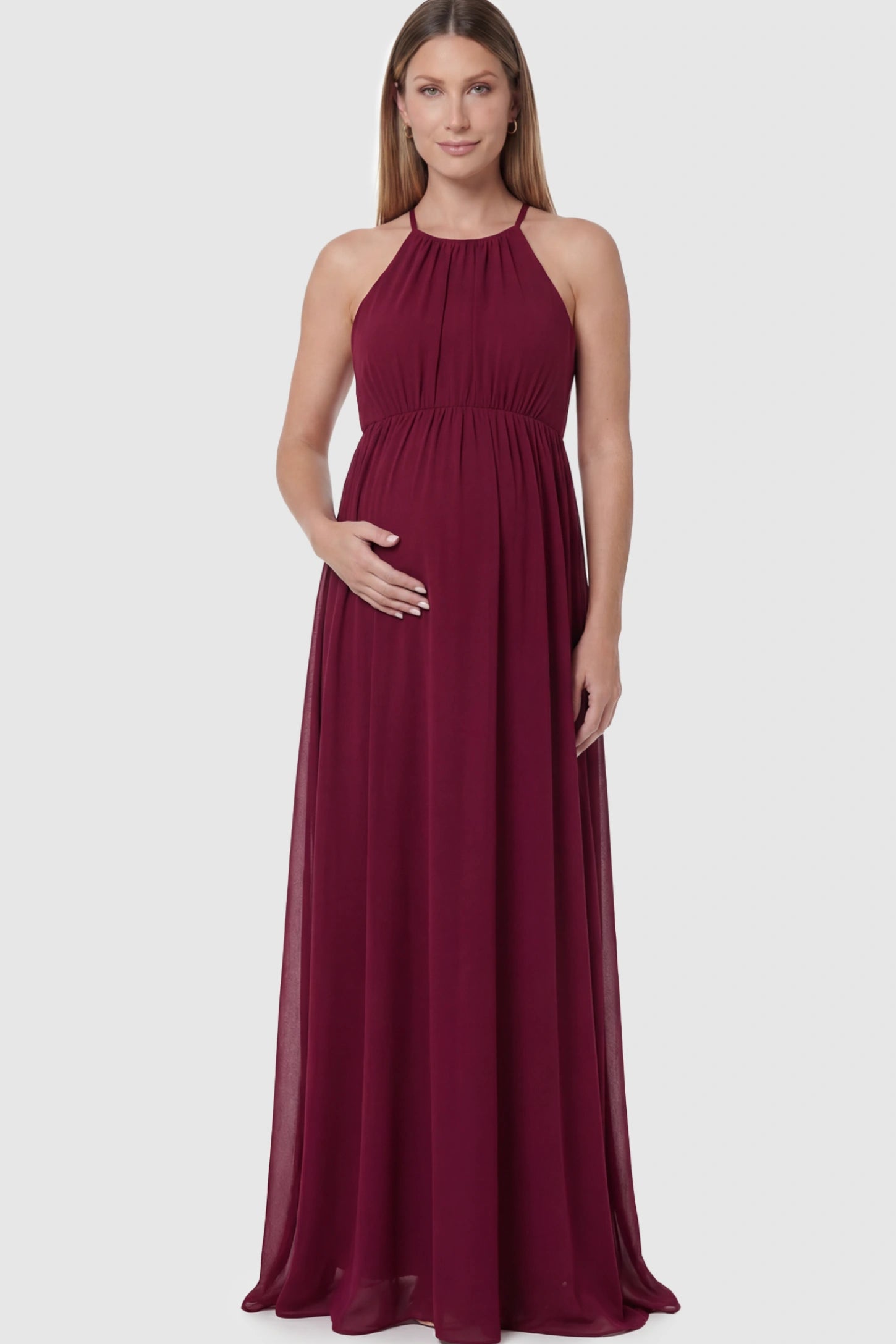Pleated Mesh Sleeveless Maternity Photoshoot Dress in Burgundy featuring a high-neckline and flowing skirt on a pregnant model.