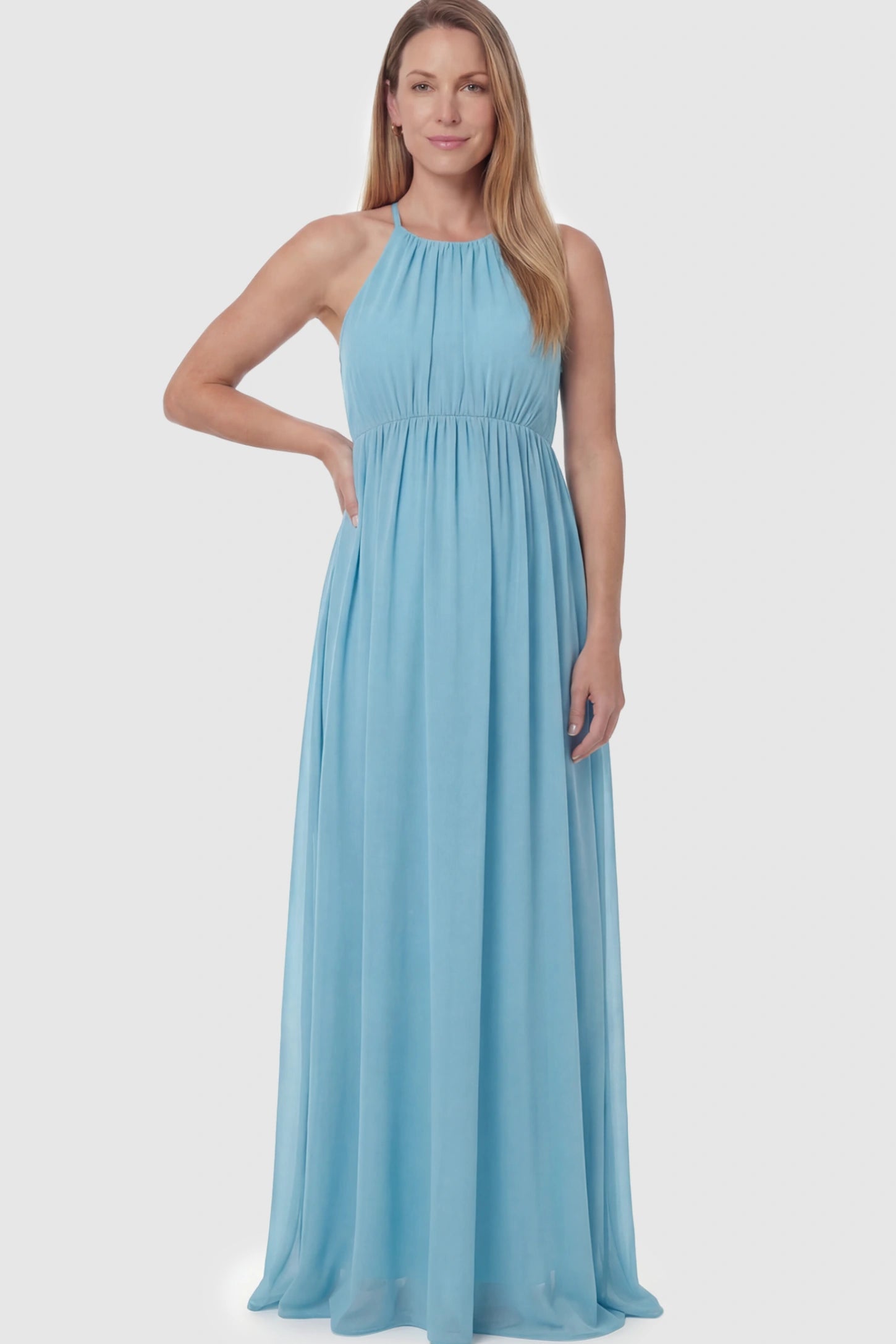 Pleated Mesh Sleeveless Maternity Photoshoot Dress Pleated Mesh Sleeveless Maternity Photoshoot Dress in Light Blue featuring a high-neckline and flowing skirt on a postpartum model.