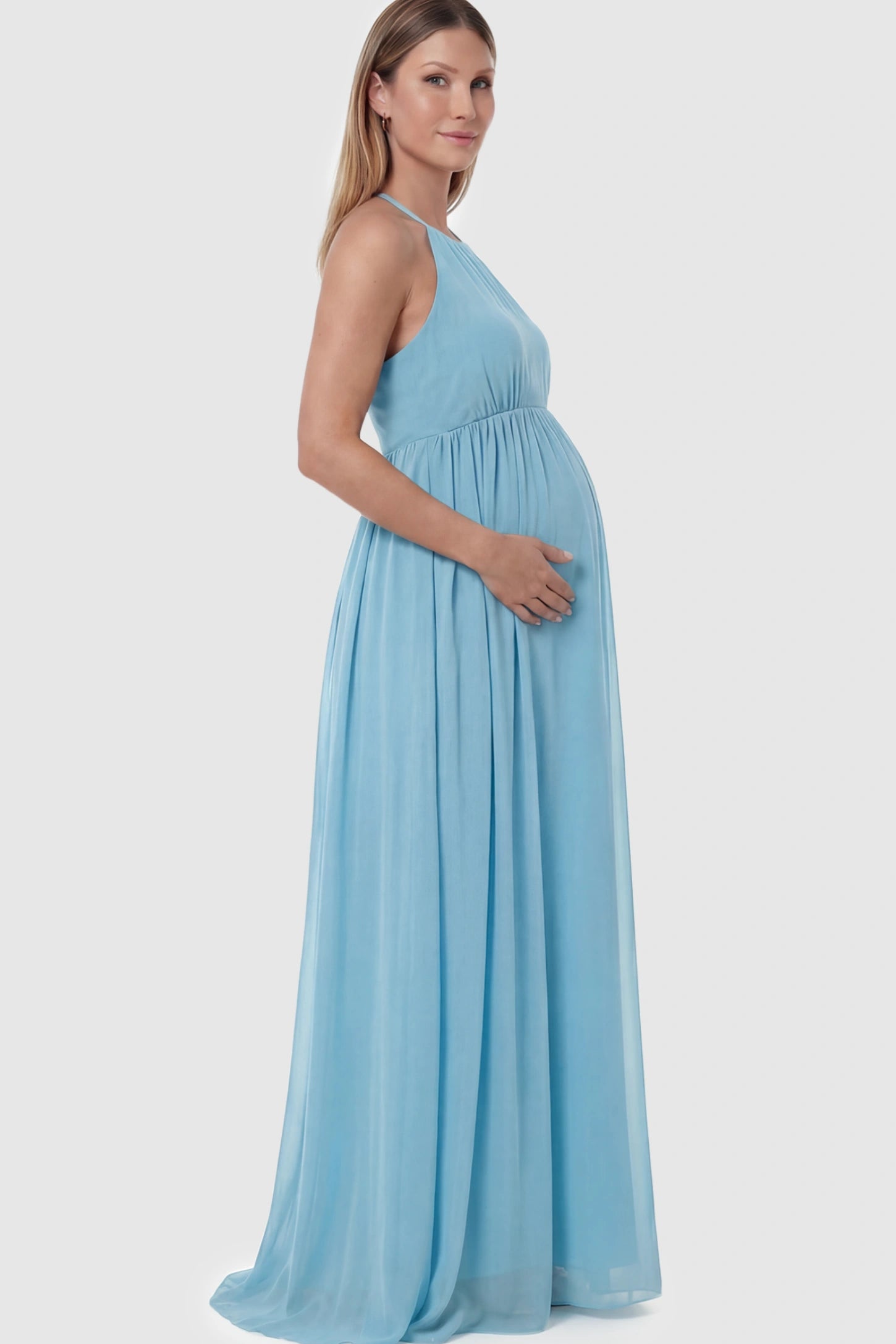 Pleated Mesh Sleeveless Maternity Photoshoot Dress Pleated Mesh Sleeveless Maternity Photoshoot Dress in Light Blue featuring a high-neckline and flowing skirt on a pregnant model.