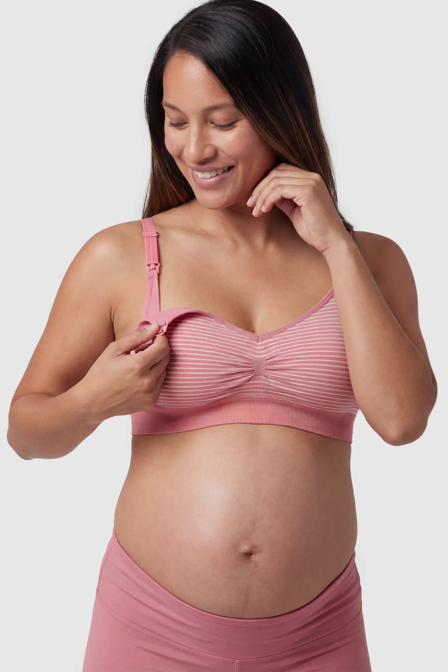 Striped Seamless Clip Down Maternity Nursing Bra Striped Seamless Clip-Down Nursing Bra in pink featuring a ruched center and nursing clips on a pregnant model.