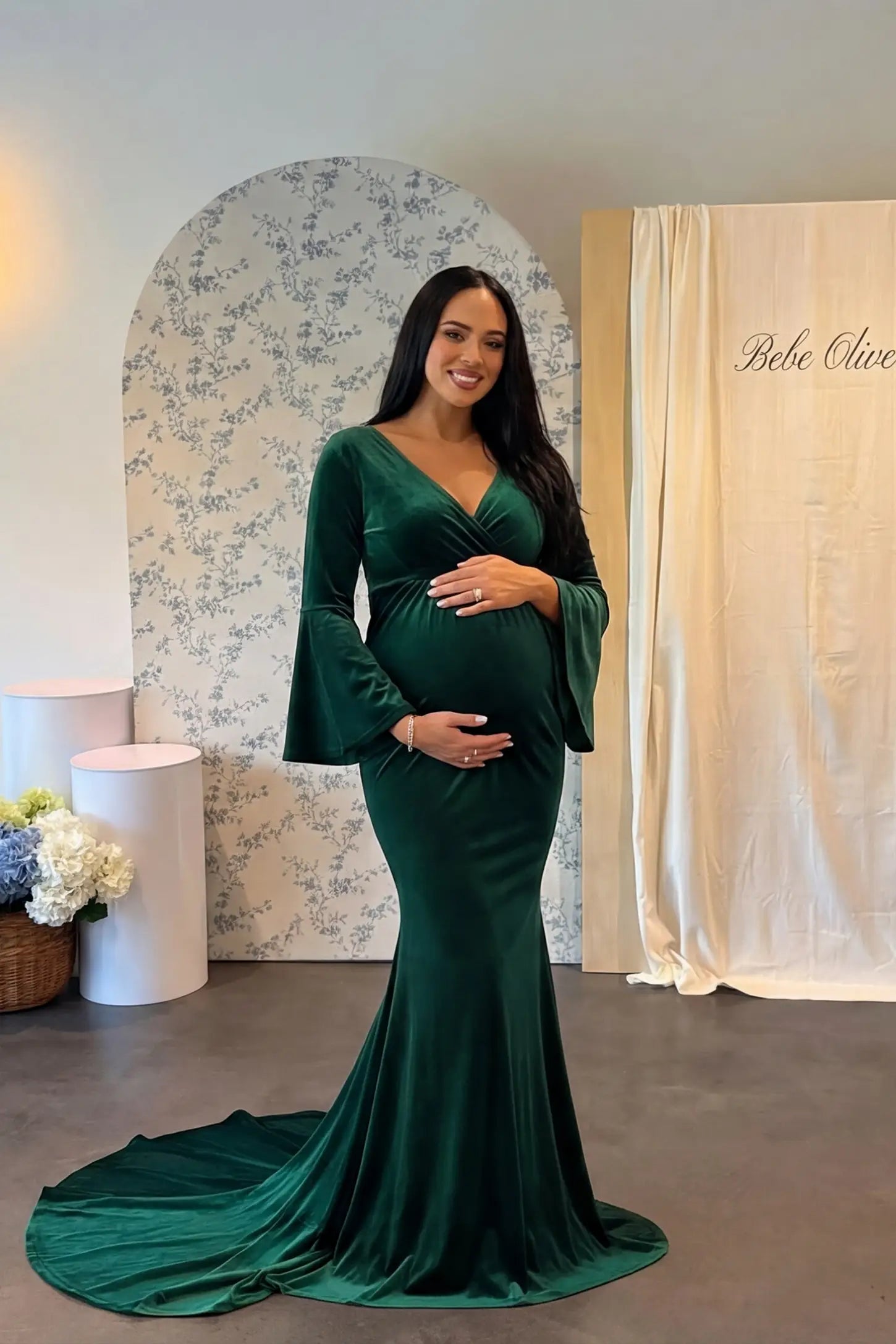Velvet Long Bell Sleeve Maternity Mermaid Gown Velvet Long Bell Sleeve Maternity Mermaid Gown in Green featuring a front-facing pregnant silhouette with a long train.