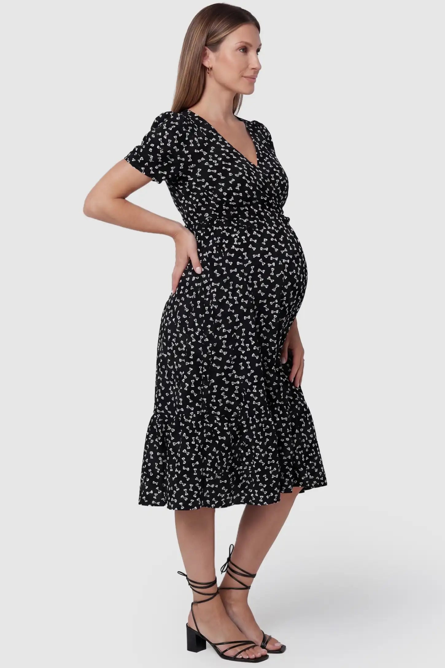 Bow-Print Wrap Midi Maternity Dress in bow-tie pattern featuring a tiered hem on a side-profile pregnant model.