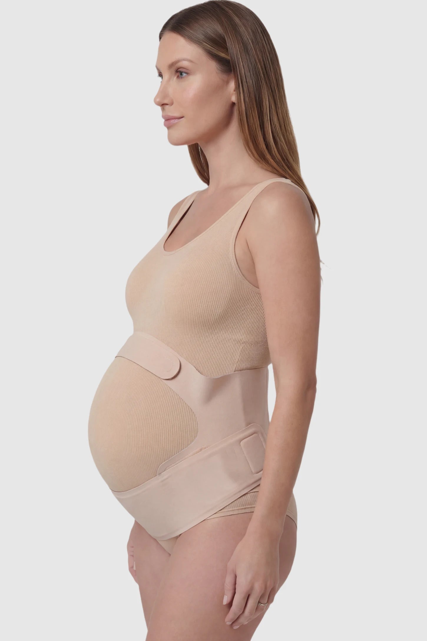Adjustable Ergonomic Maternity Belly Support Band in Skin featuring an adjustable ergonomic dual-strap design on a pregnant model showing side.