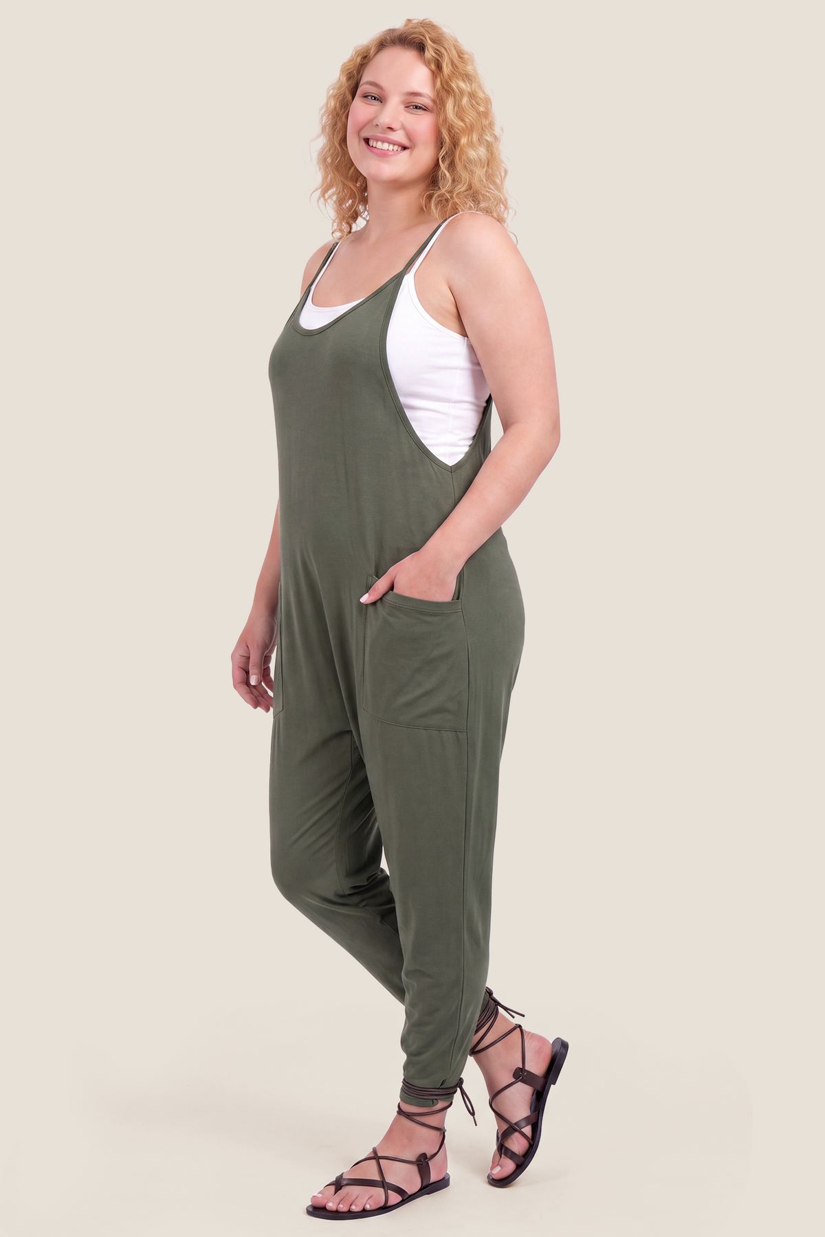 Adjustable Strap Pocketed Relaxed Maternity Jumpsuit Adjustable Strap Pocketed Maternity Jumpsuit in Army Green with functional side pockets on a pregnant model, side view.