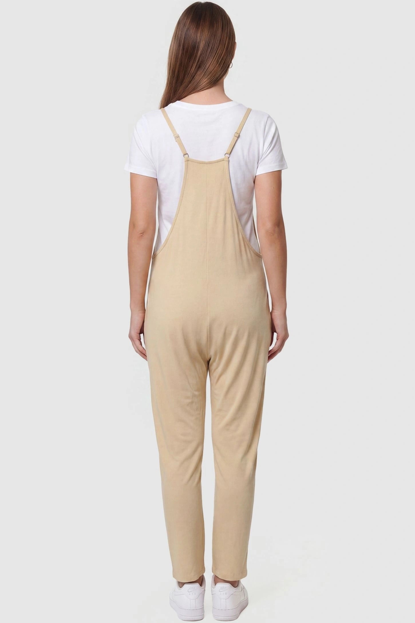 Adjustable Strap Pocketed Relaxed Maternity Jumpsuit Adjustable Strap Pocketed Maternity Jumpsuit in Beige featuring adjustable shoulder straps on a pregnant model, back view.