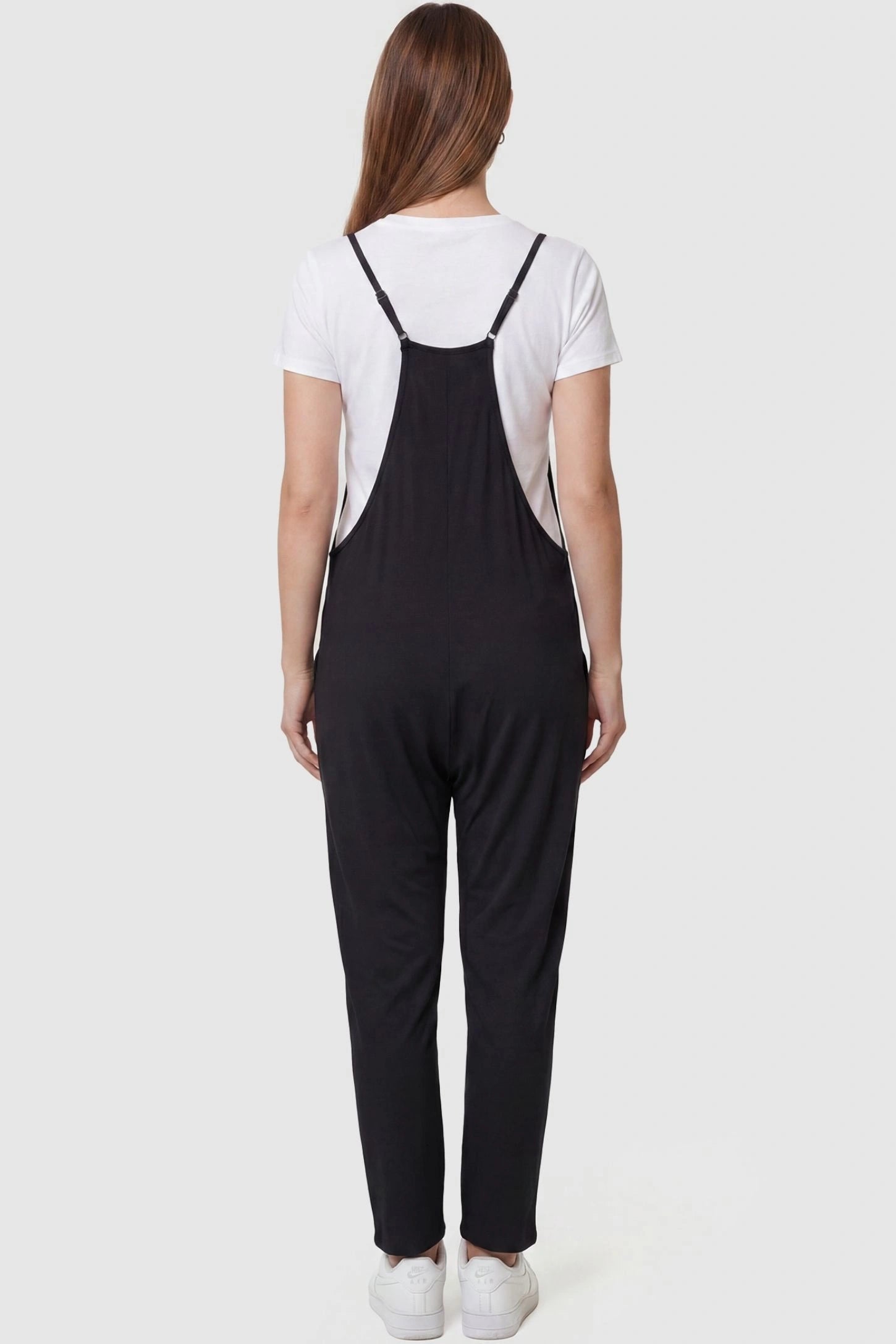 Adjustable Strap Pocketed Relaxed Maternity Jumpsuit Adjustable Strap Pocketed Maternity Jumpsuit in Black featuring adjustable shoulder straps on a pregnant model, back view.