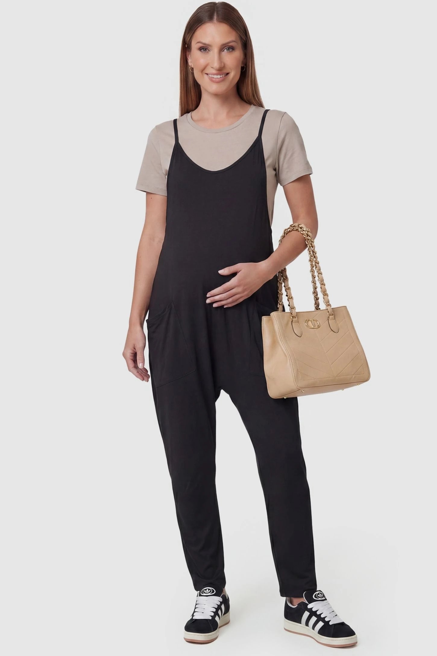 Adjustable Strap Pocketed Relaxed Maternity Jumpsuit Adjustable Strap Pocketed Maternity Jumpsuit in Black featuring a relaxed fit on a pregnant model, front view.