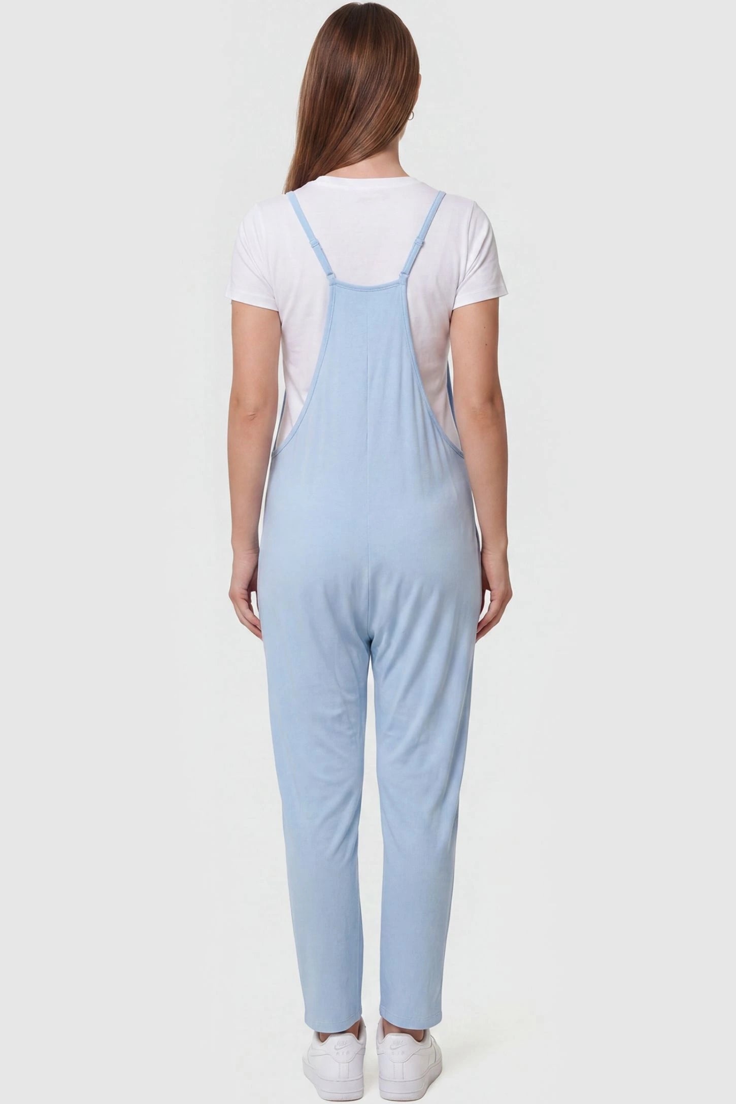 Adjustable Strap Pocketed Relaxed Maternity Jumpsuit Adjustable Strap Pocketed Maternity Jumpsuit in Light Blue featuring adjustable shoulder straps on a pregnant model, back view.