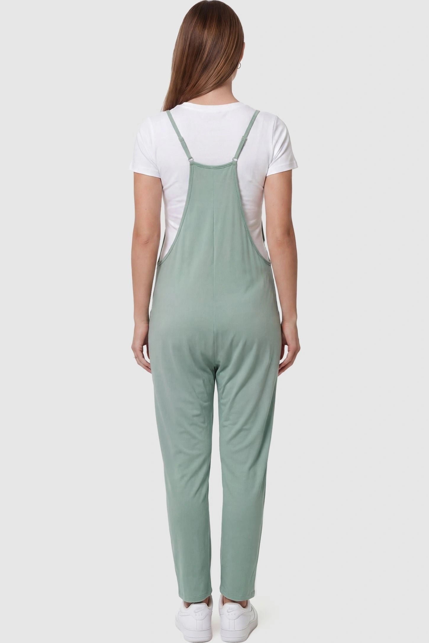 Adjustable Strap Pocketed Relaxed Maternity Jumpsuit Adjustable Strap Pocketed Maternity Jumpsuit in Light Green featuring adjustable shoulder straps on a pregnant model, back view.