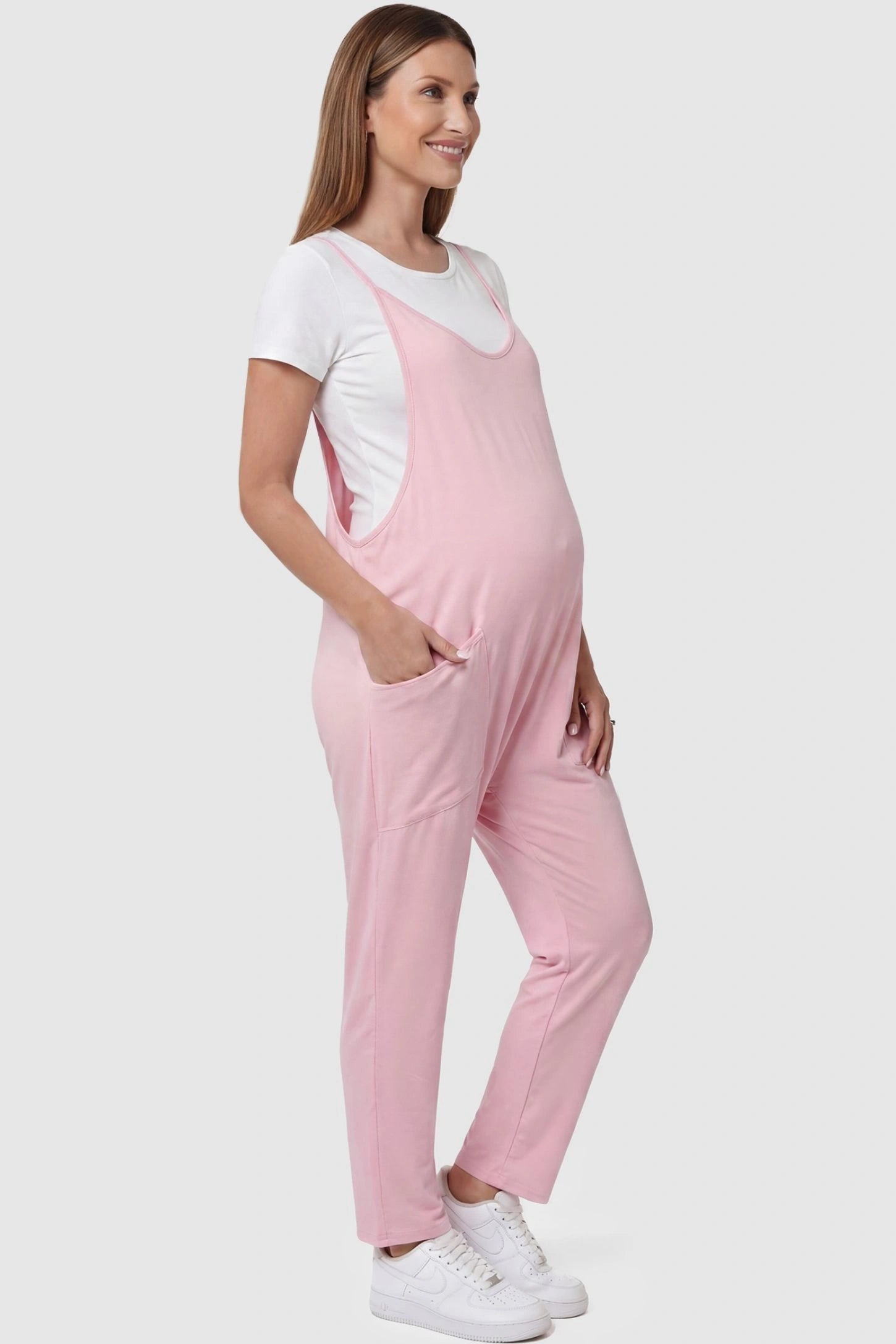 Adjustable Strap Pocketed Relaxed Maternity Jumpsuit Adjustable Strap Pocketed Maternity Jumpsuit in Pink with functional side pockets on a pregnant model, side view.
