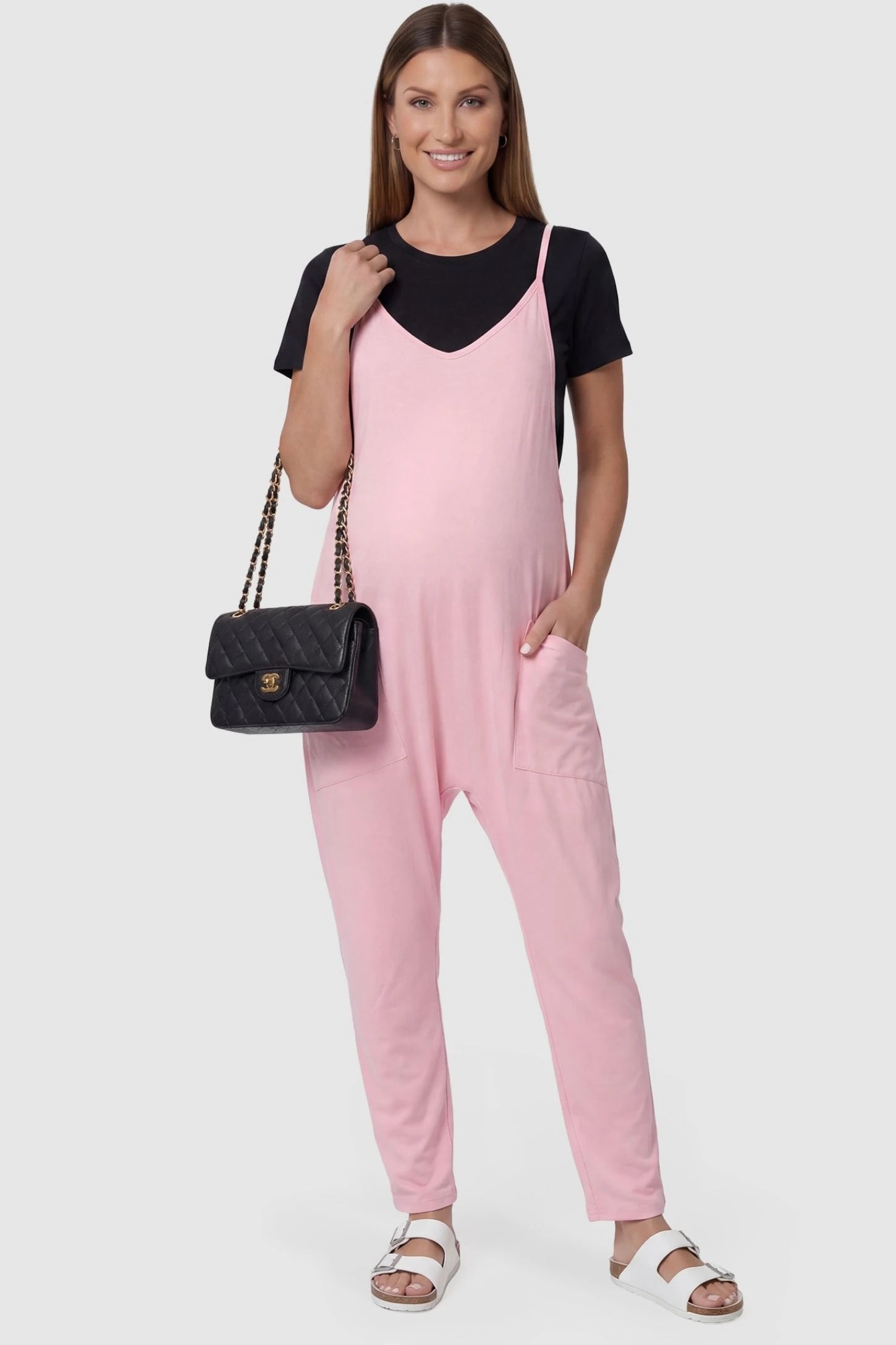 Adjustable Strap Pocketed Relaxed Maternity Jumpsuit Adjustable Strap Pocketed Maternity Jumpsuit in Pink featuring a relaxed fit on a pregnant model, front view.