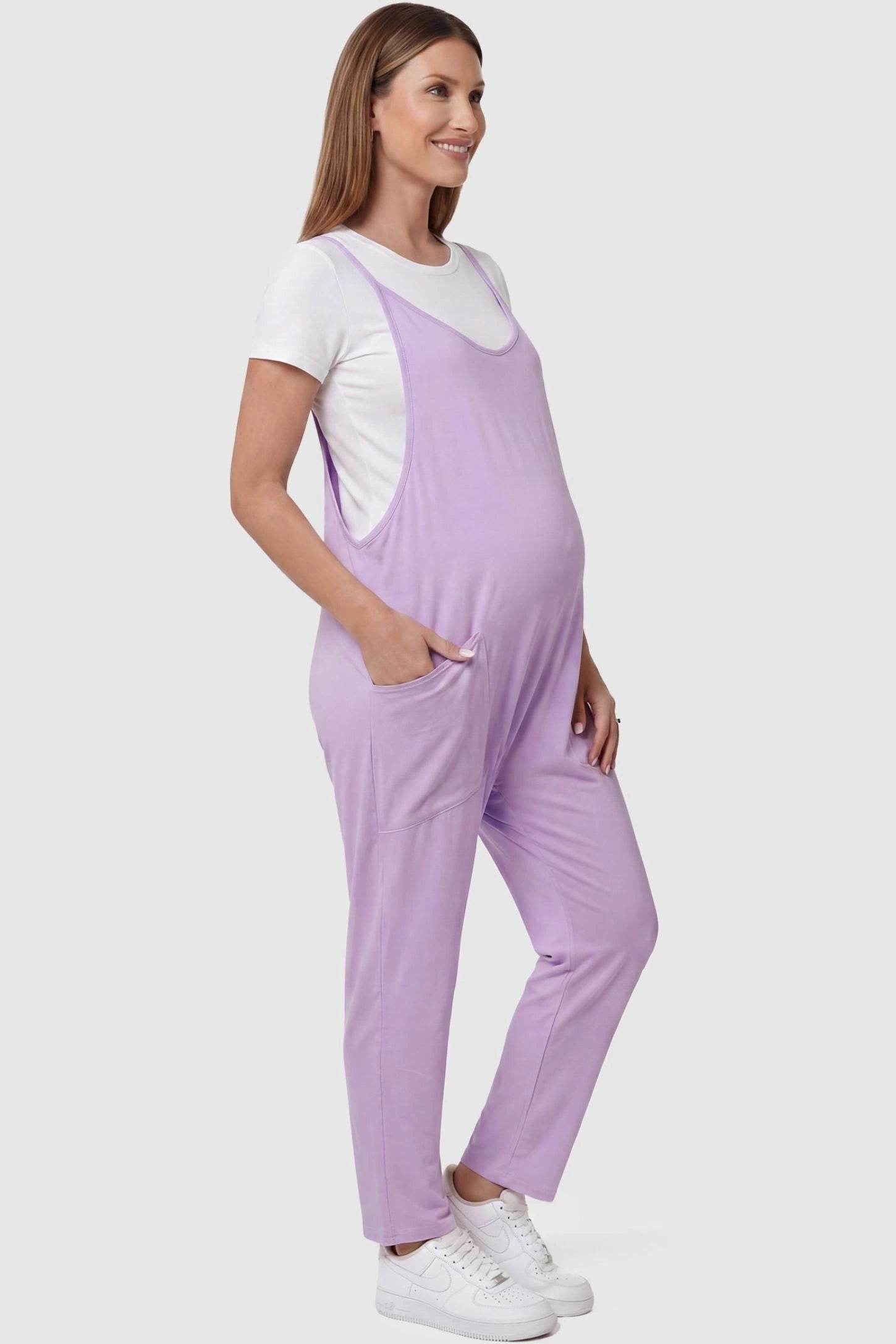 Adjustable Strap Pocketed Relaxed Maternity Jumpsuit Adjustable Strap Pocketed Maternity Jumpsuit in Purple with functional side pockets on a pregnant model, side view.
