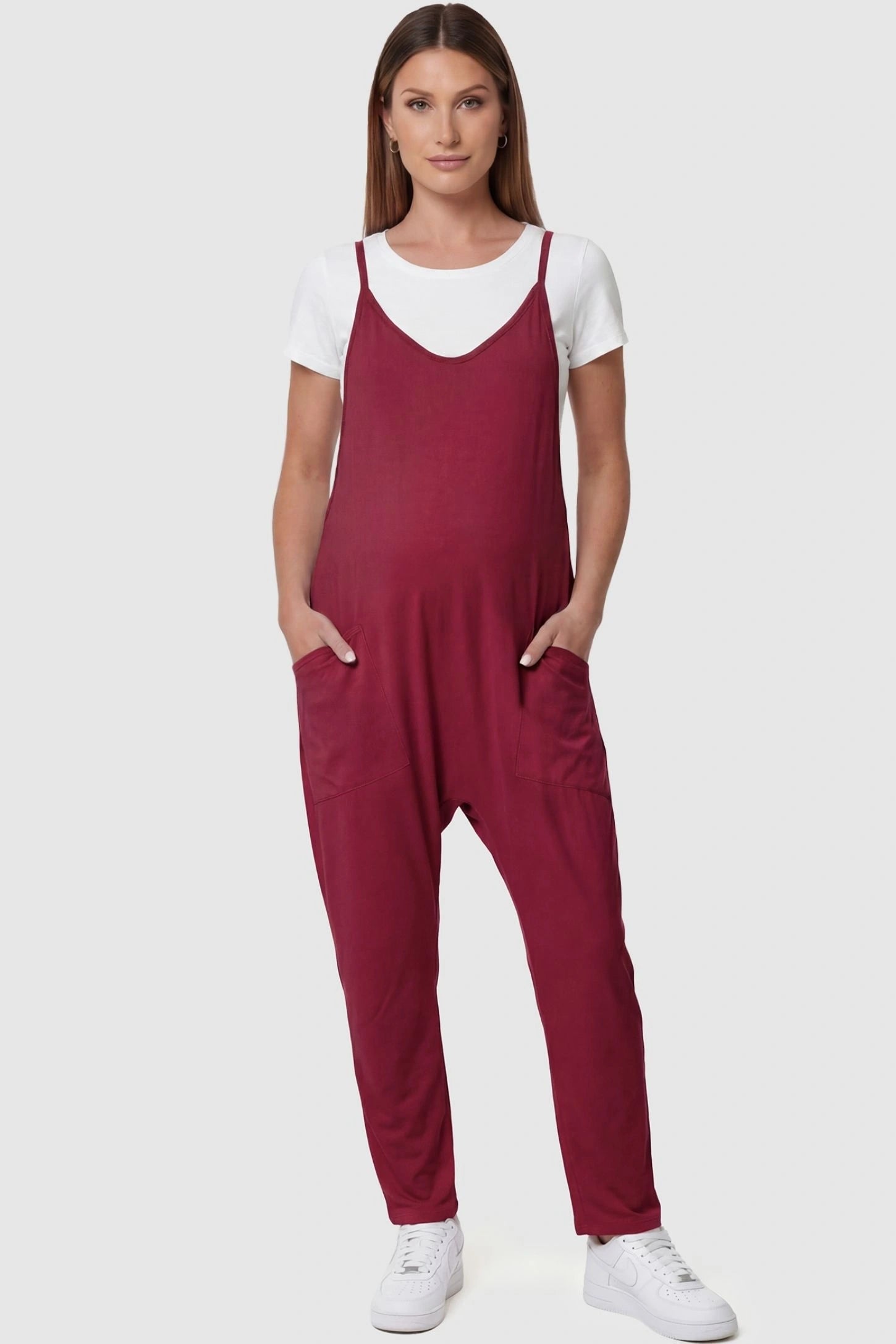 Adjustable Strap Pocketed Relaxed Maternity Jumpsuit Adjustable Strap Pocketed Maternity Jumpsuit in Wine Red featuring a relaxed fit on a pregnant model, front view.
