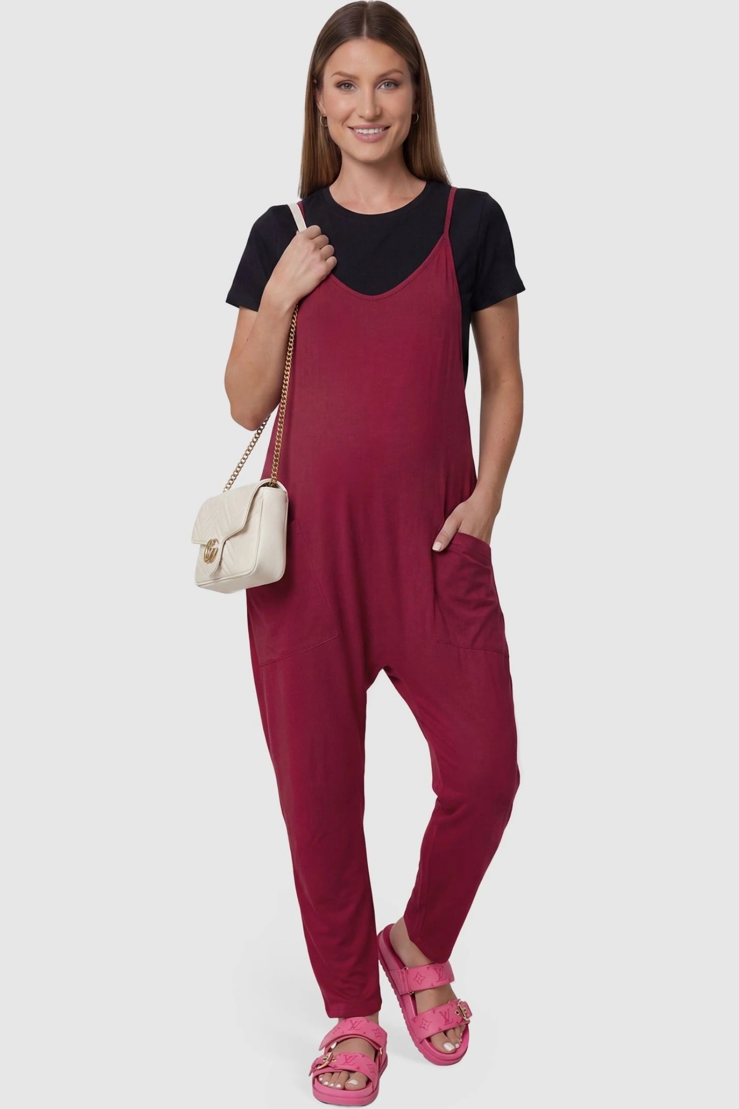 Adjustable Strap Pocketed Relaxed Maternity Jumpsuit Adjustable Strap Pocketed Maternity Jumpsuit in Wine Red featuring a relaxed fit on a pregnant model, front view.