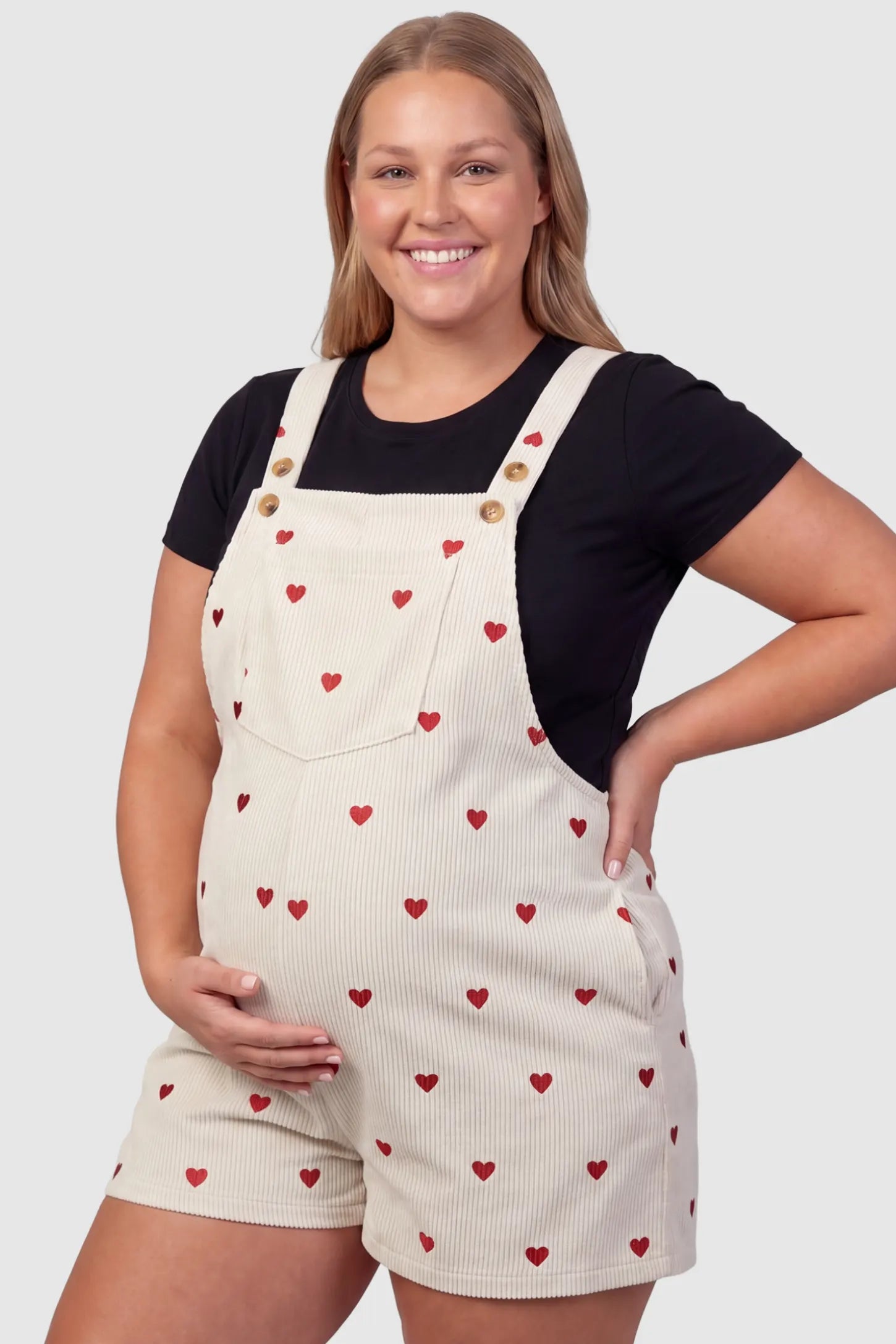 Adjustable Waist Front Pocket Maternity Short Overalls Adjustable Waist Front Pocket Maternity Short Overalls in red featuring an adjustable waist and front bib pocket on a plus size pregnant model, front view.