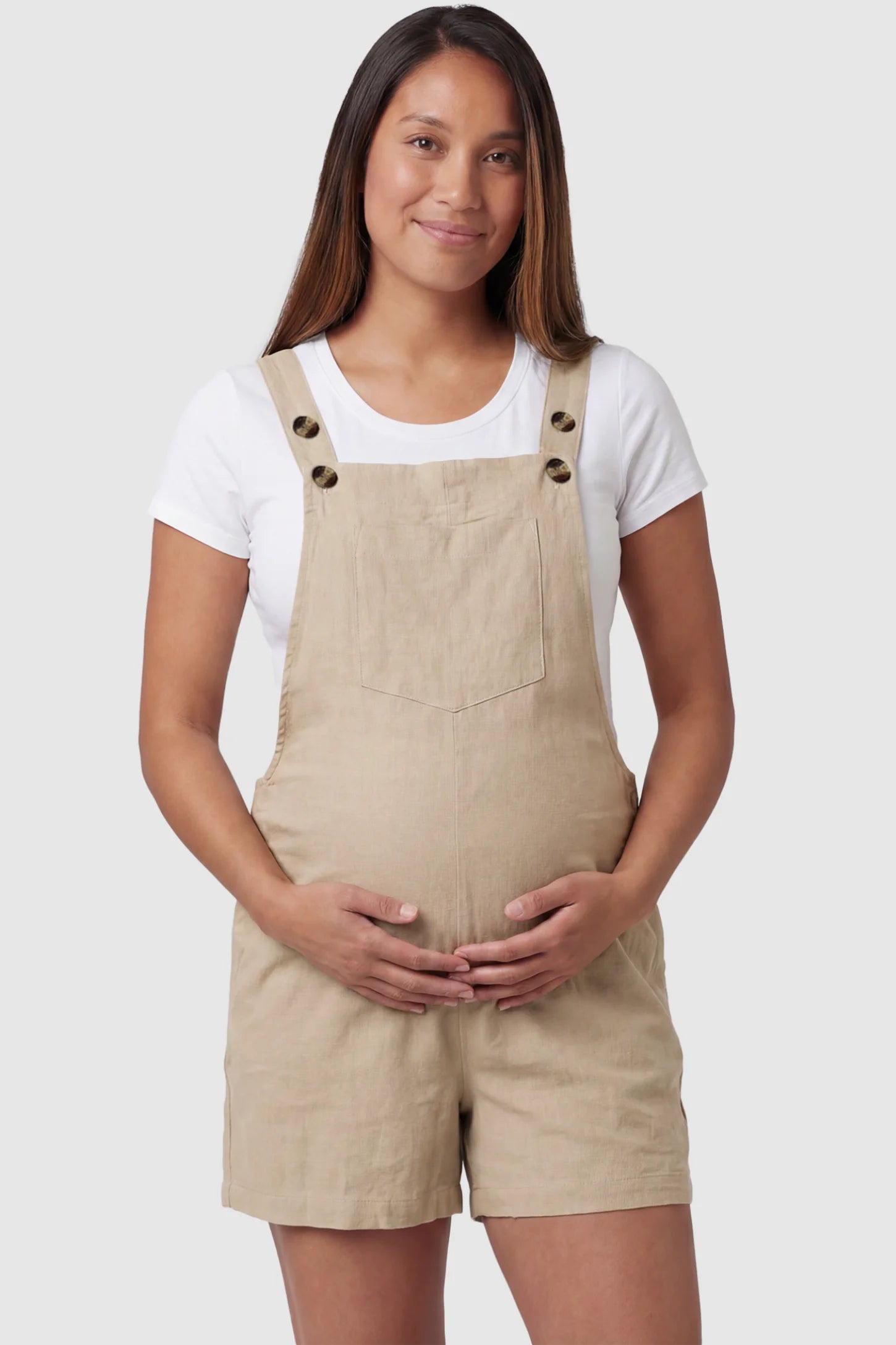 Adjustable Waist Pocketed Maternity Short Overalls Adjustable Waist Pocketed Maternity Short Overalls in Beige featuring a bib pocket on a pregnant model, front view.