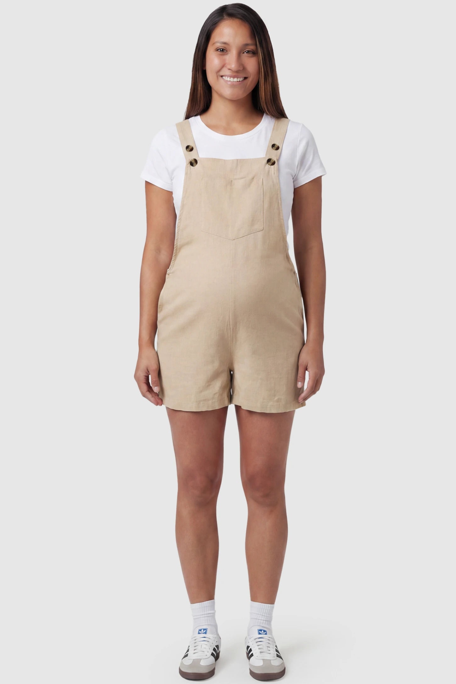 Adjustable Waist Pocketed Maternity Short Overalls Adjustable Waist Pocketed Maternity Short Overalls in Beige featuring a bib pocket on a pregnant model, full body view.
