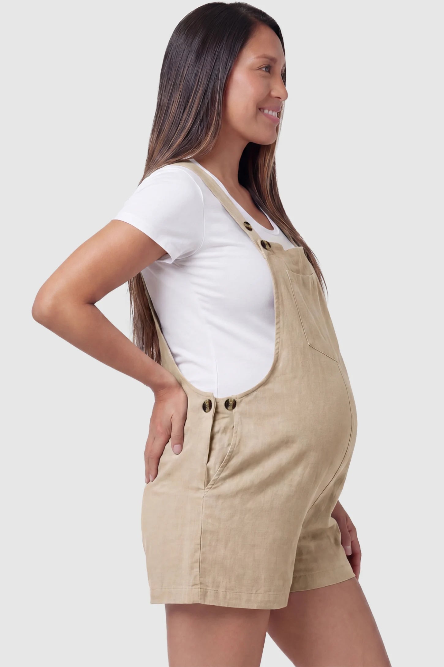 Adjustable Waist Pocketed Maternity Short Overalls Adjustable Waist Pocketed Maternity Short Overalls in Beige featuring functional side buttons on a pregnant model, side view.