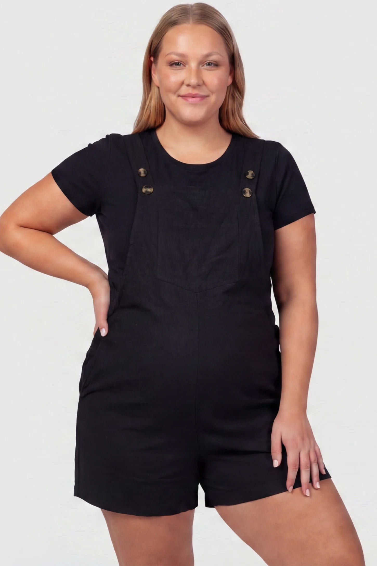 Adjustable Waist Pocketed Maternity Short Overalls Adjustable Waist Pocketed Maternity Short Overalls in Black featuring a bib pocket on a plus size pregnant model, front view.