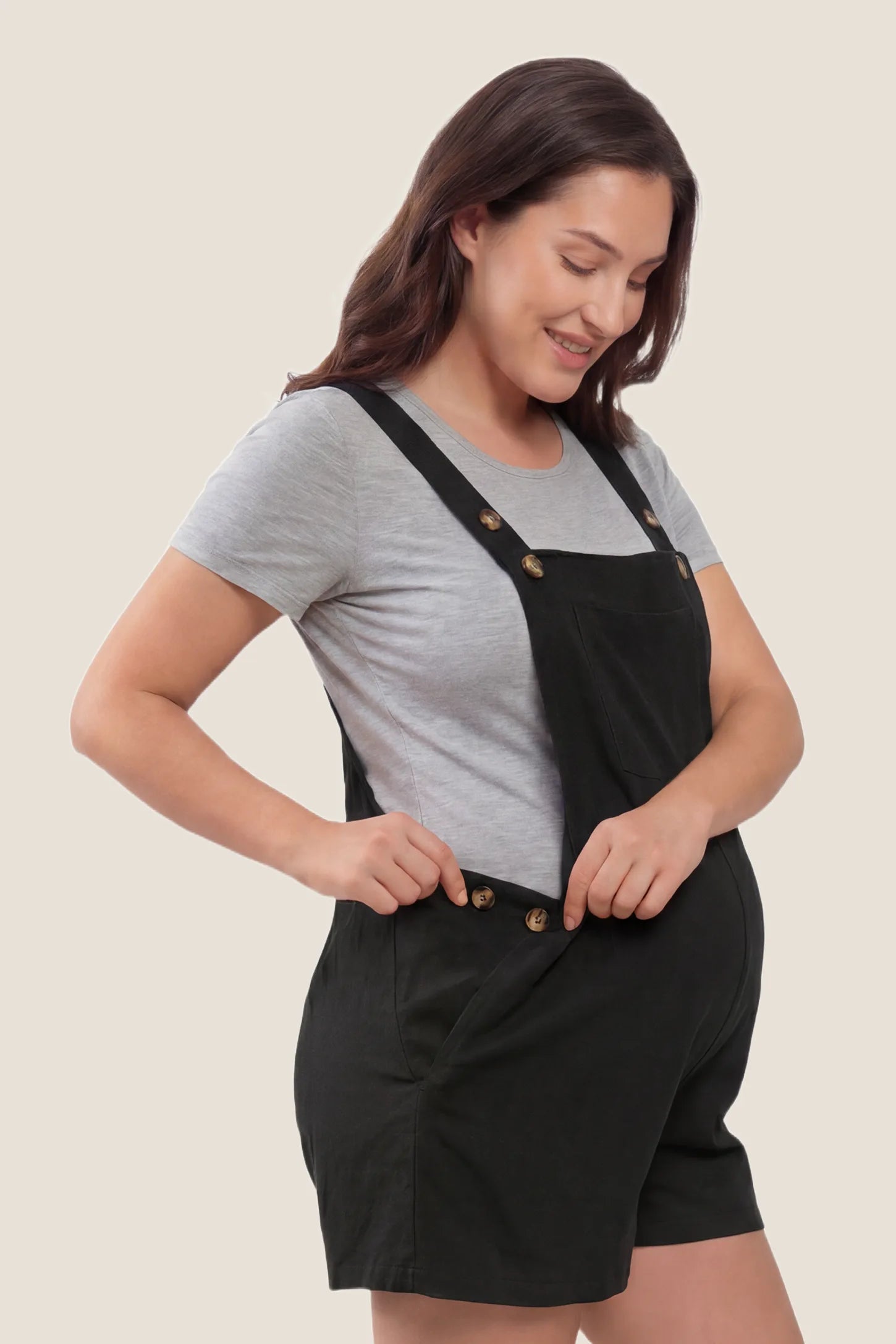 Adjustable Waist Pocketed Maternity Short Overalls Side view of the black Adjustable Waist Pocketed Maternity Short Overalls designed to fit comfortably throughout pregnancy.