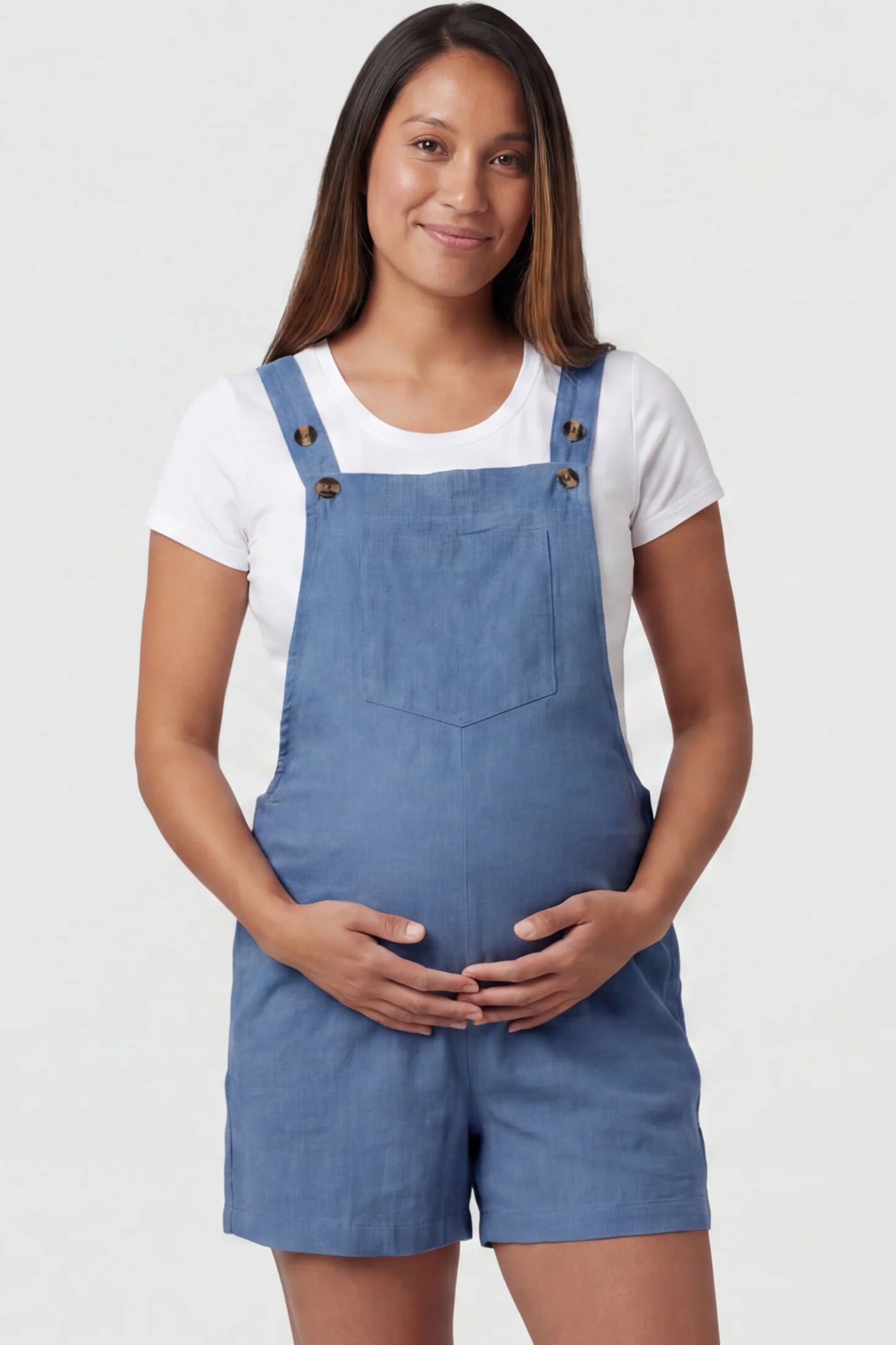 Adjustable Waist Pocketed Maternity Short Overalls Adjustable Waist Pocketed Maternity Short Overalls in Blue featuring a bib pocket on a pregnant model, front view.