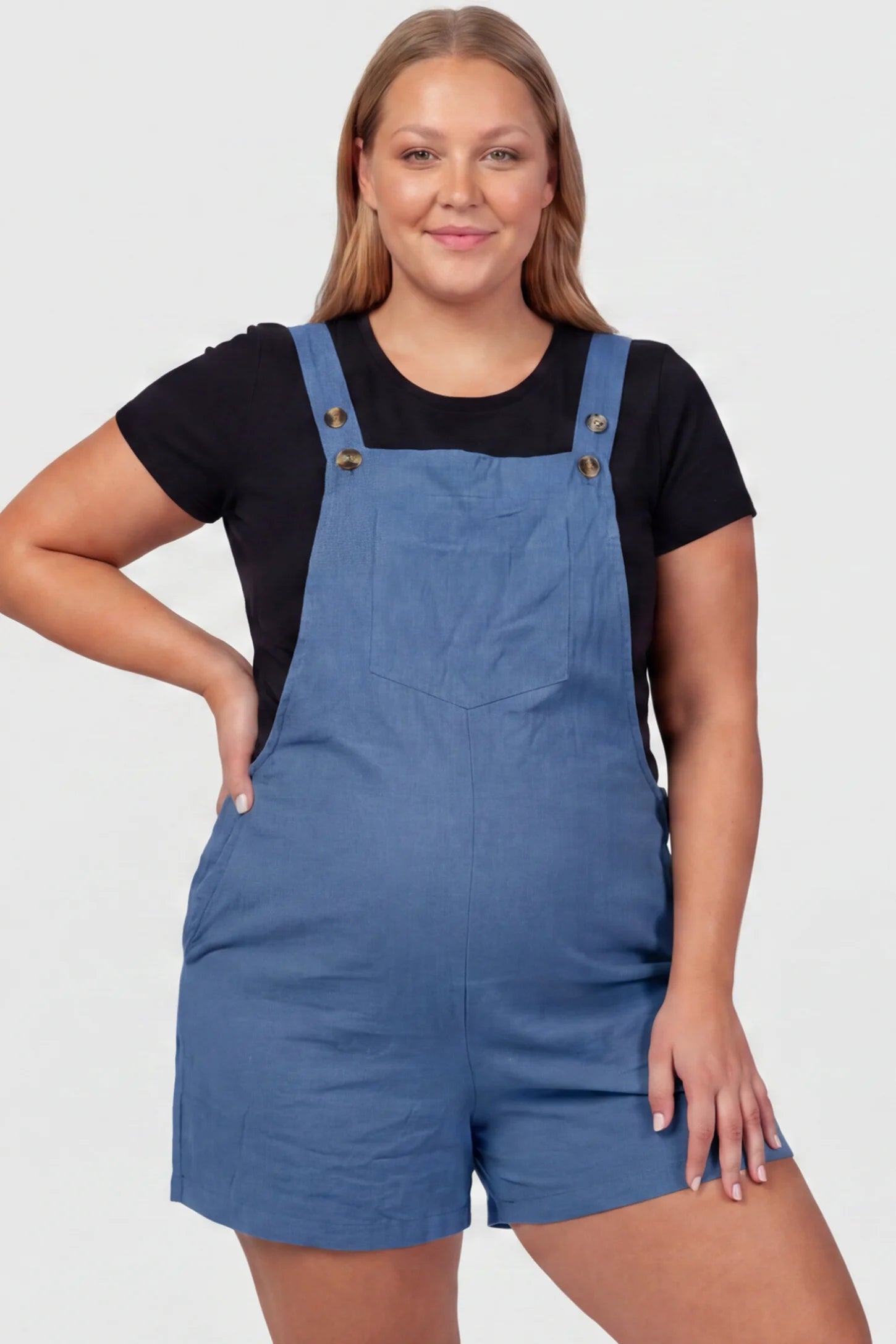 Adjustable Waist Pocketed Maternity Short Overalls Adjustable Waist Pocketed Maternity Short Overalls in Blue featuring a bib pocket on a plus size pregnant model, front view.