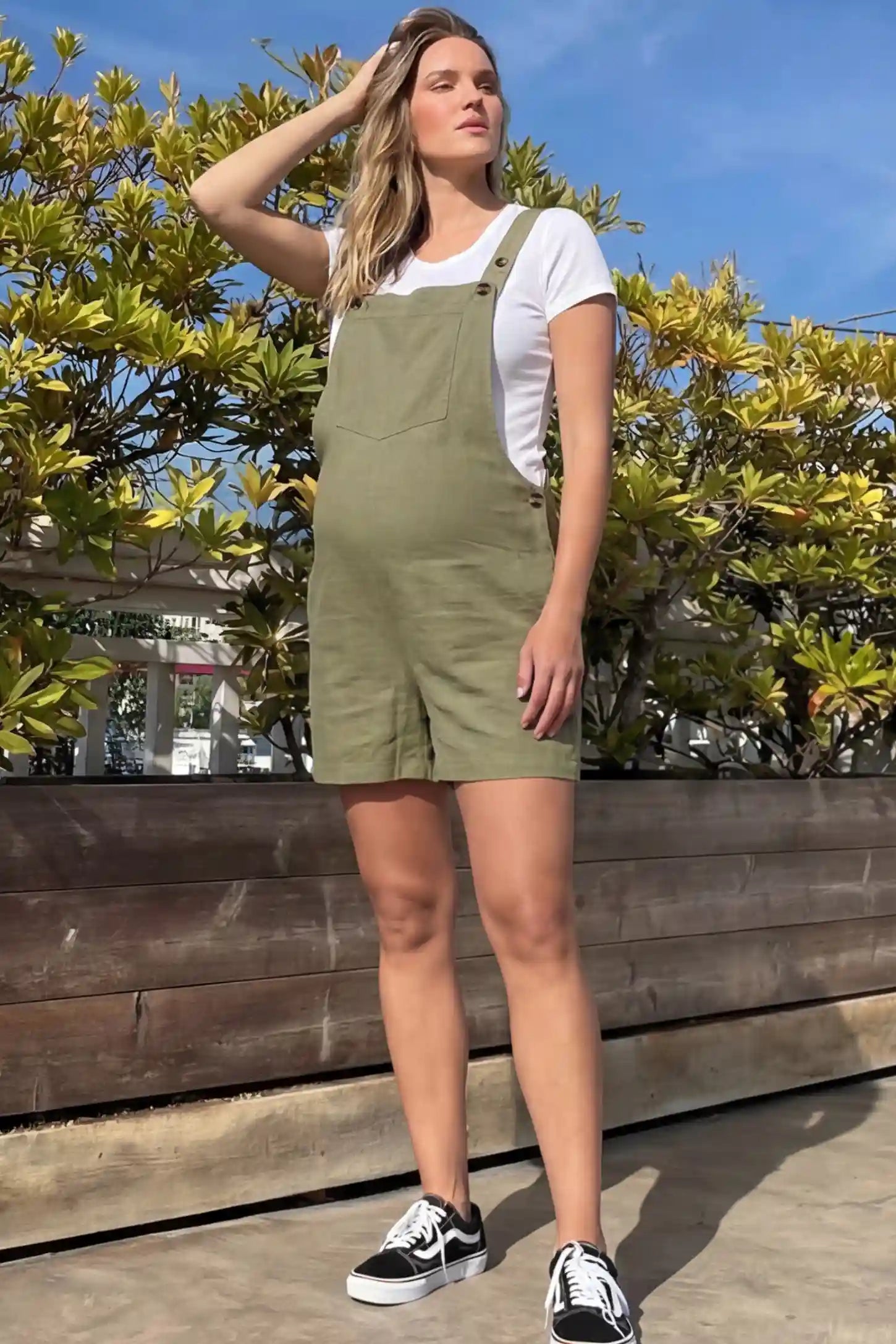 Adjustable Waist Pocketed Maternity Short Overalls Adjustable Waist Pocketed Maternity Short Overalls in Green featuring a bib pocket on a pregnant woman in outdoor setting, front view.