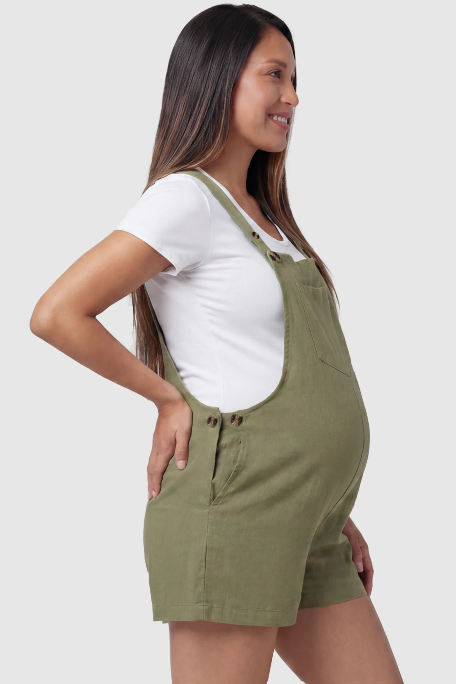 Adjustable Waist Pocketed Maternity Short Overalls Adjustable Waist Pocketed Maternity Short Overalls in Green featuring functional side buttons on a pregnant model, side view.