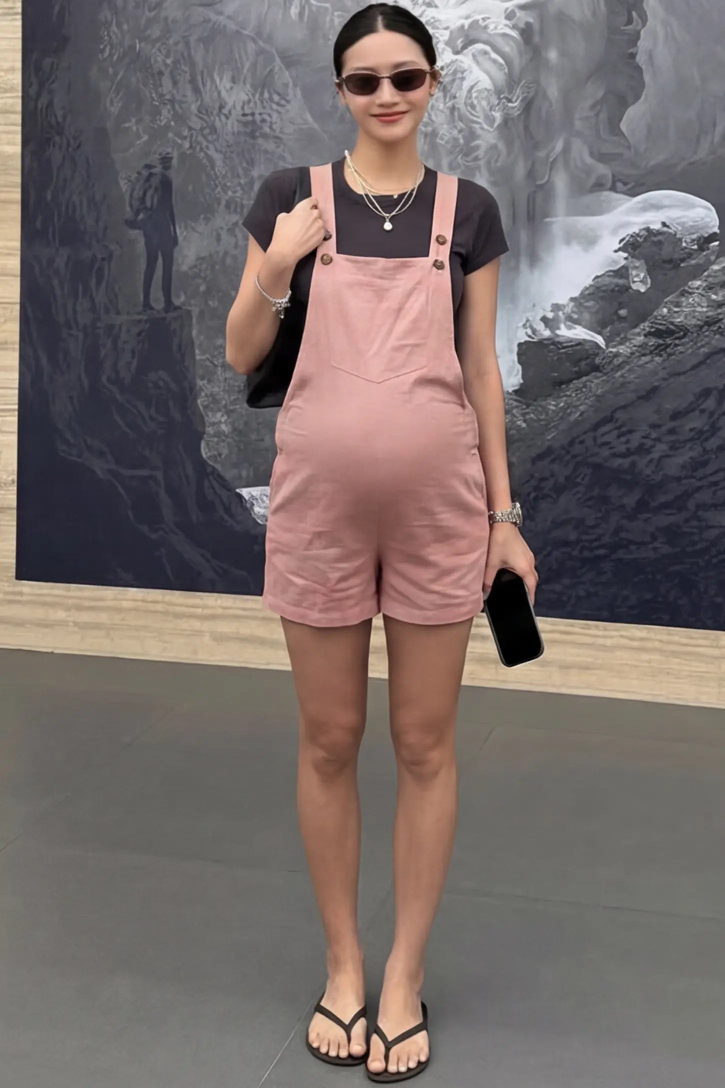 Adjustable Waist Pocketed Maternity Short Overalls Adjustable Waist Pocketed Maternity Short Overalls in Pink featuring a bib pocket on a pregnant woman in indoor setting, front view.