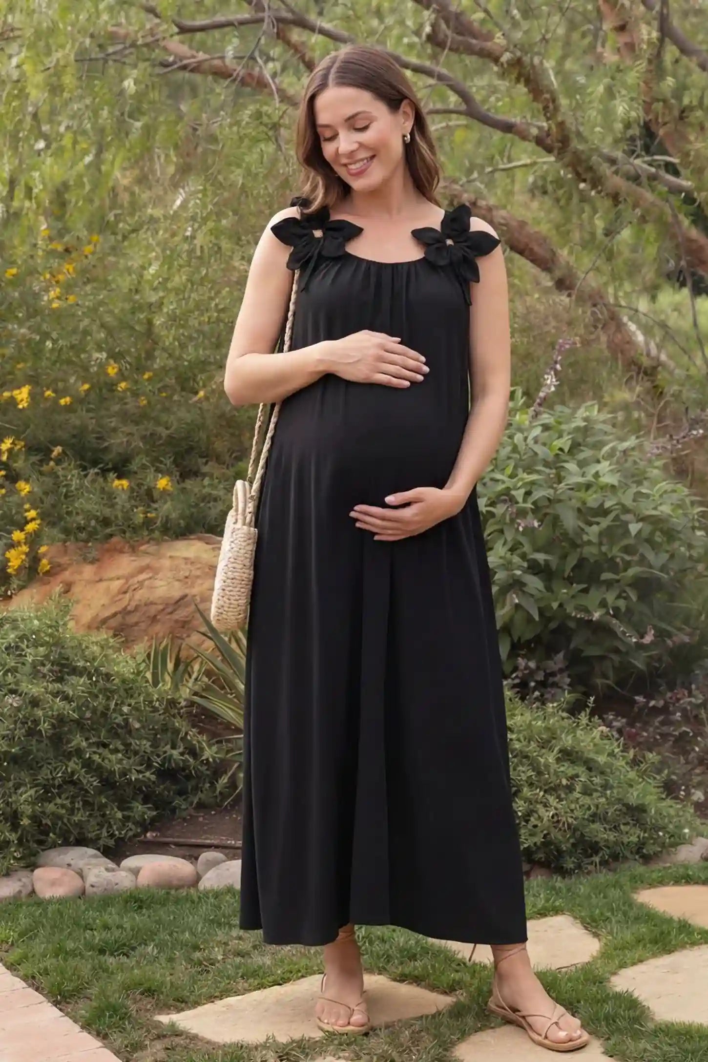 Bow Strap A-Line Maternity Dress Black Bow Strap A-Line Maternity Dress in a sunny garden setting on a pregnant model holding her bump.